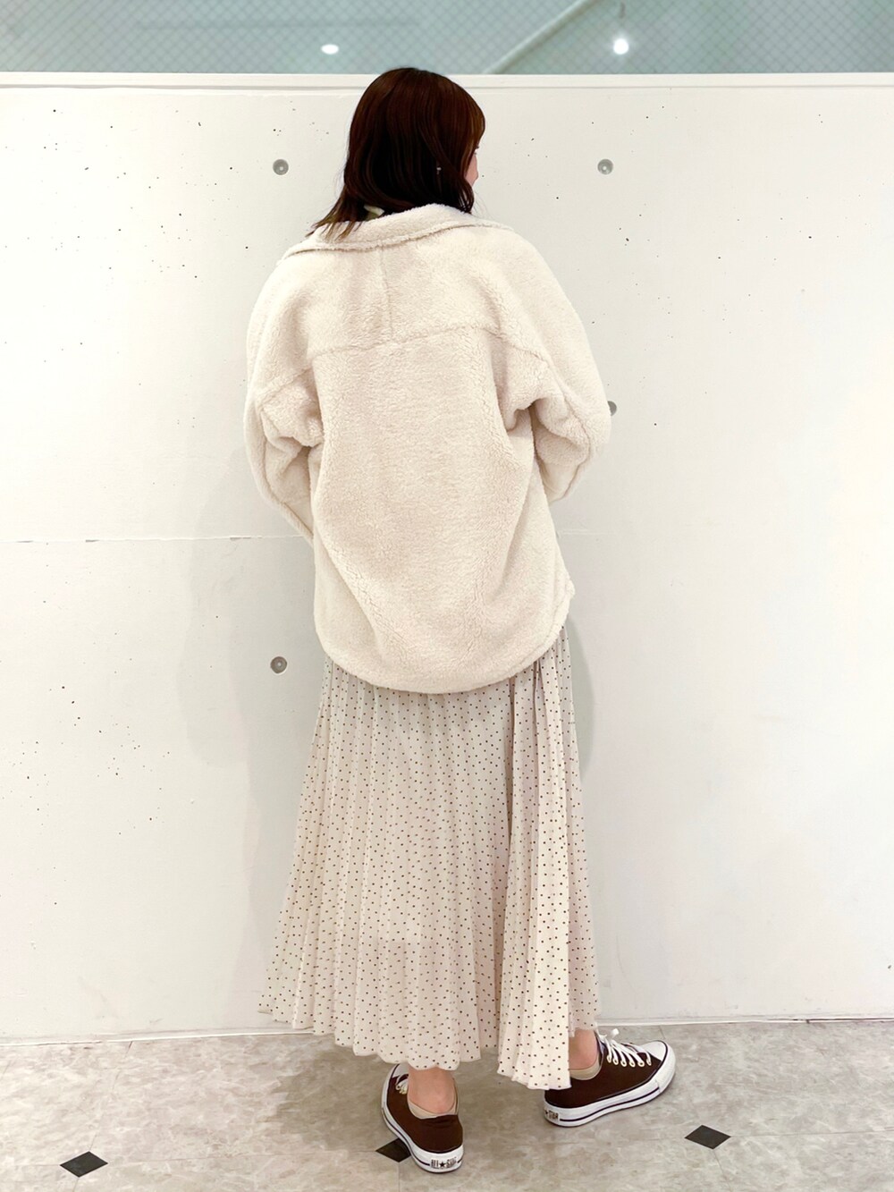 ホワイト系のブルゾン、ホワイト系のスカート、イエロー系のニット/セーターを着用したレディースの冬コーディネートの2枚目の写真