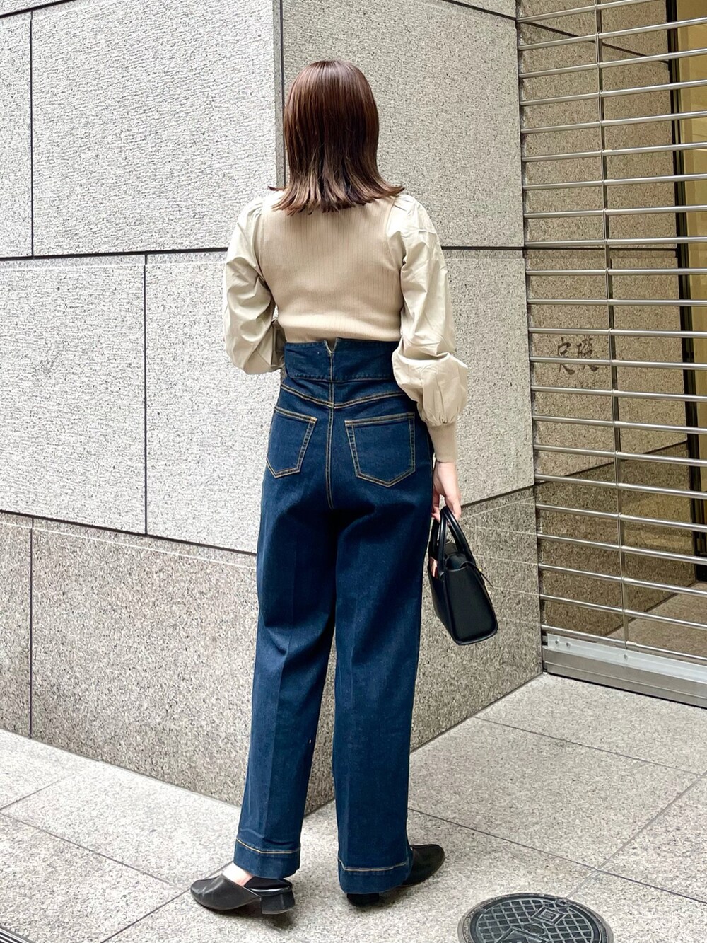 ベージュ系のニット/セーター、ブルー系のデニムパンツ、ブラック系のトートバッグを着用したレディースの春コーディネートの2枚目の写真