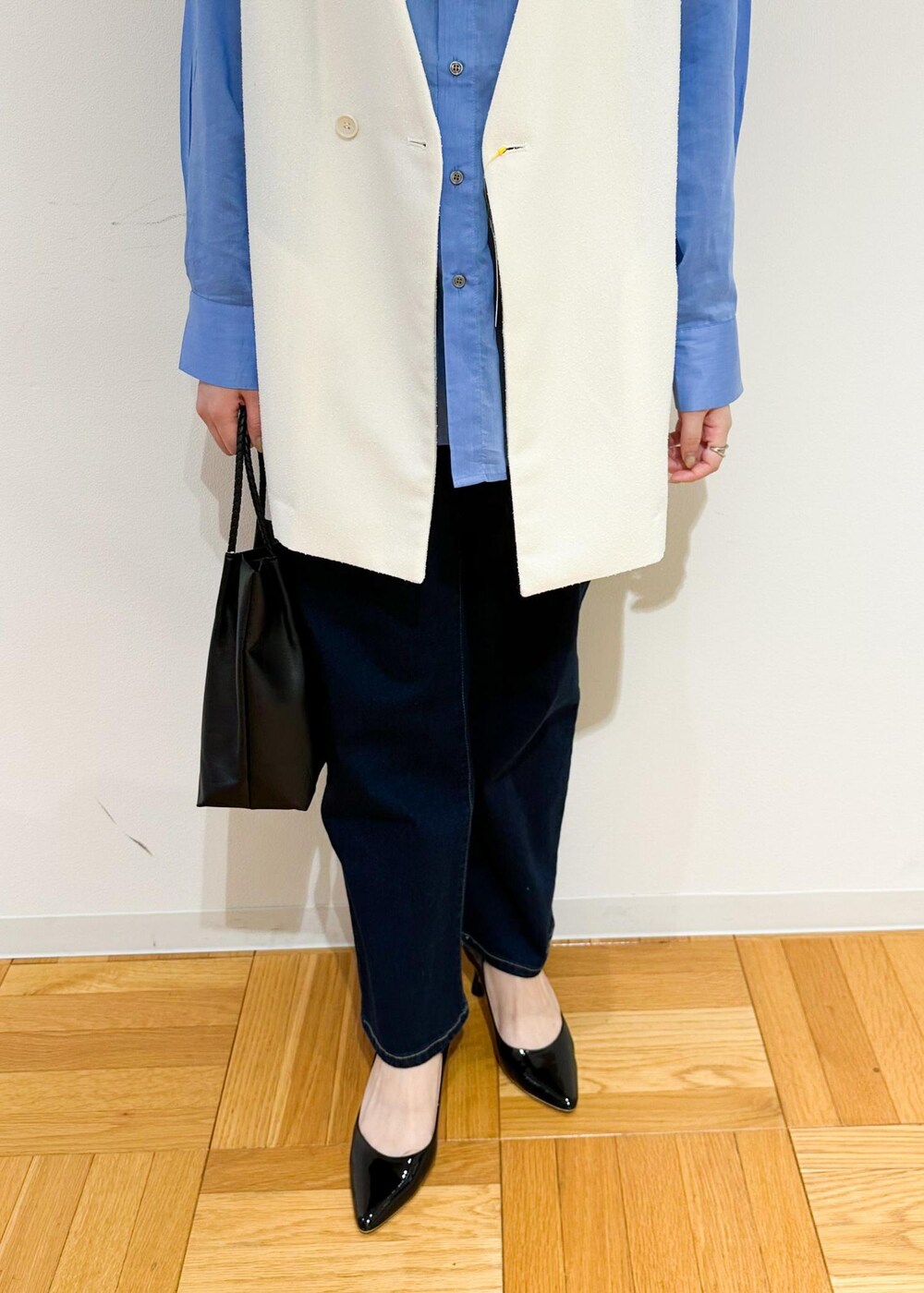 ブラック系のトートバッグ、ホワイト系のベスト、ブルー系のシャツ/ブラウスを着用したレディースの夏コーディネートの7枚目の写真