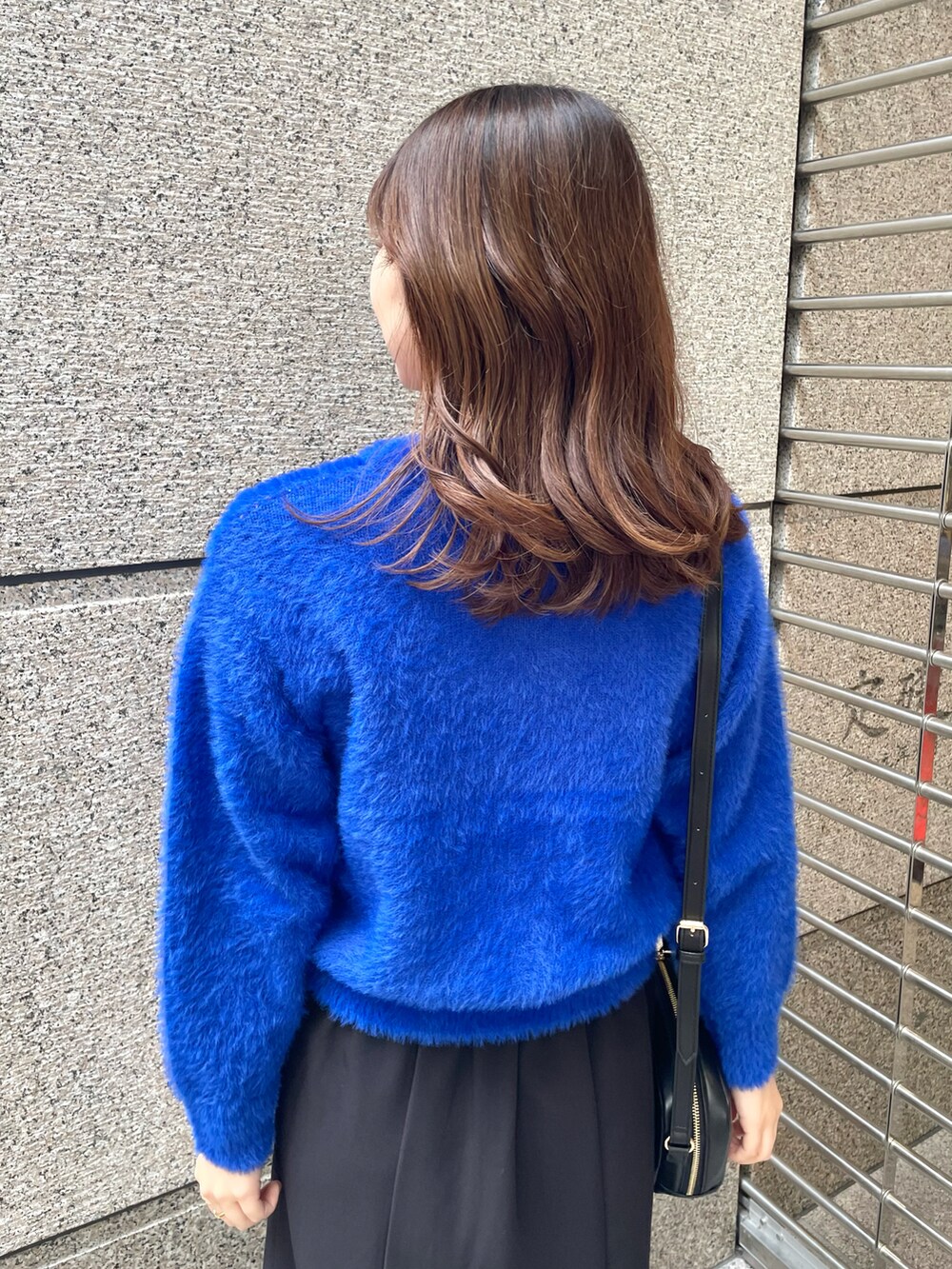 ブルー系のニット/セーター、ブラック系のスカート、ブラック系のショルダーバッグを着用したレディースの冬コーディネートの3枚目の写真