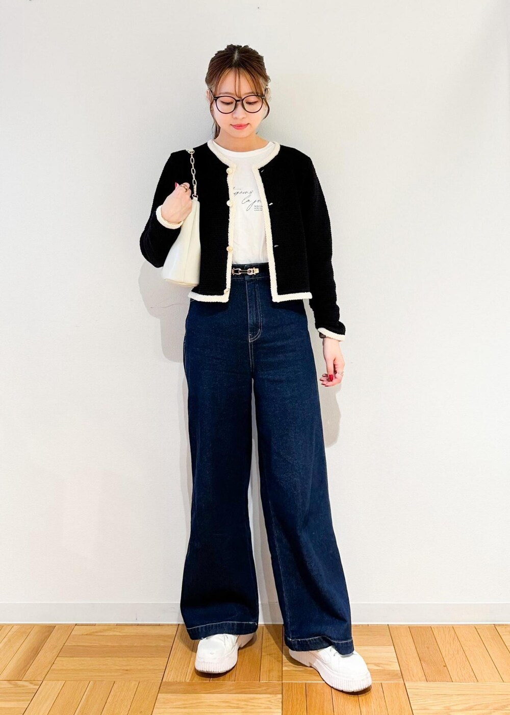 ホワイト系のショルダーバッグ、ブルー系のデニムパンツ、ブラック系のカーディガン/ボレロを着用したレディースの冬コーディネートの2枚目の写真