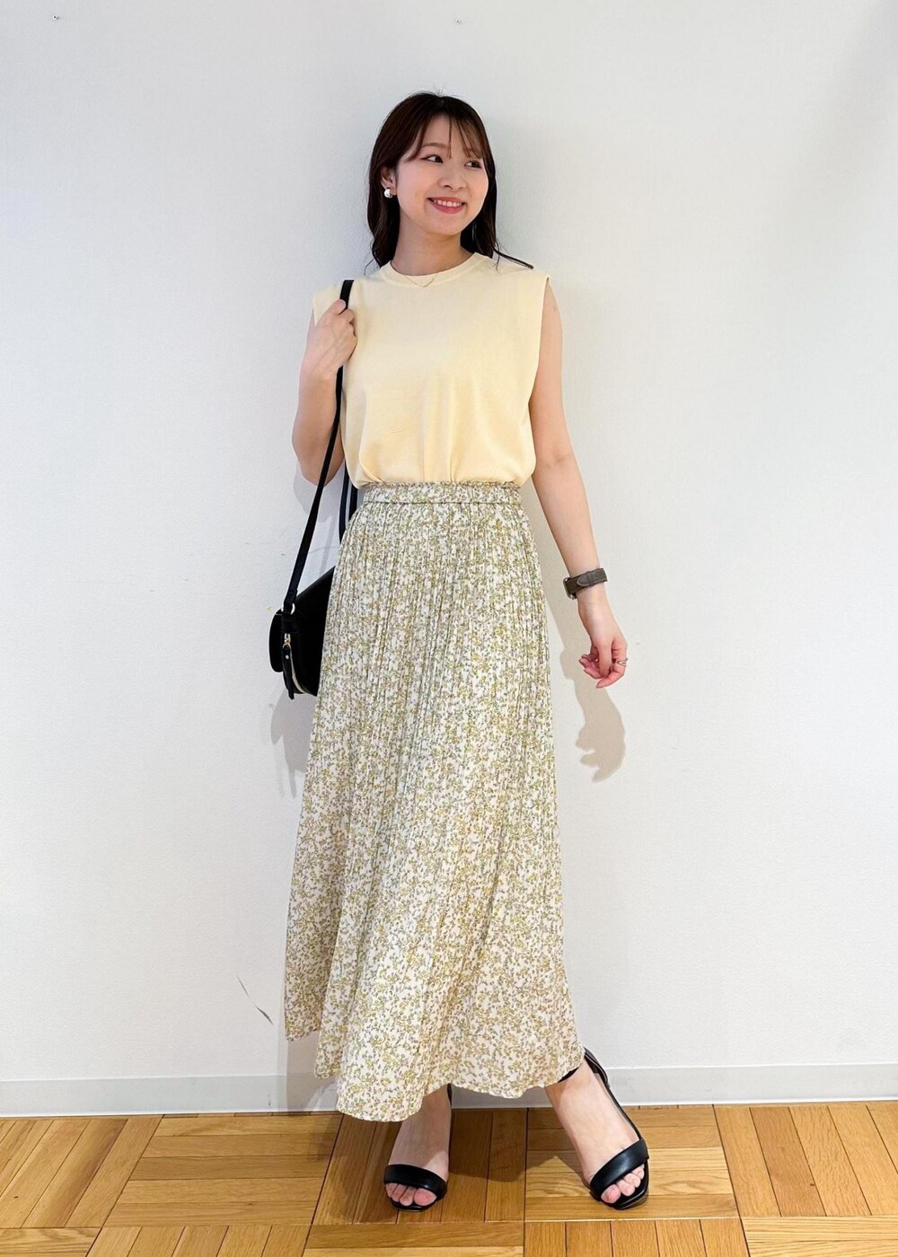ベージュ系のニット/セーター、イエロー系のスカート、ブラック系のショルダーバッグを着用したレディースの春コーディネートの2枚目の写真