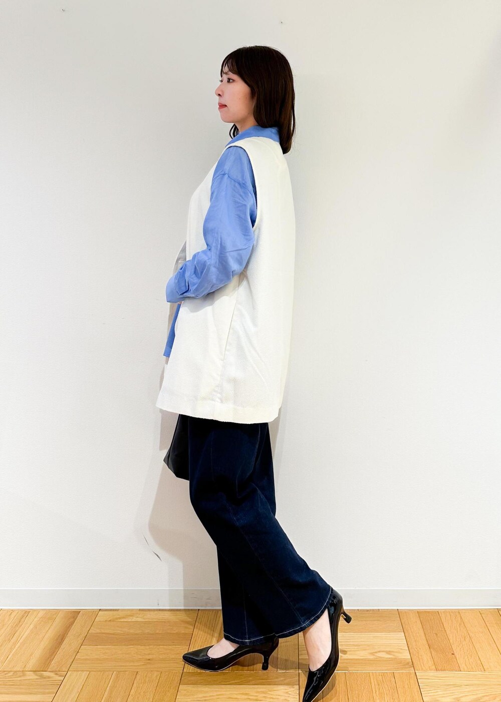 ブラック系のトートバッグ、ホワイト系のベスト、ブルー系のシャツ/ブラウスを着用したレディースの夏コーディネートの3枚目の写真