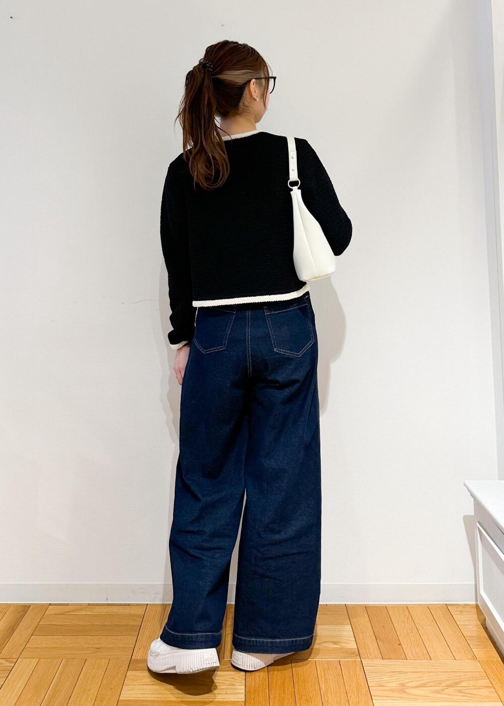 ホワイト系のショルダーバッグ、ブルー系のデニムパンツ、ブラック系のカーディガン/ボレロを着用したレディースの冬コーディネートの3枚目の写真