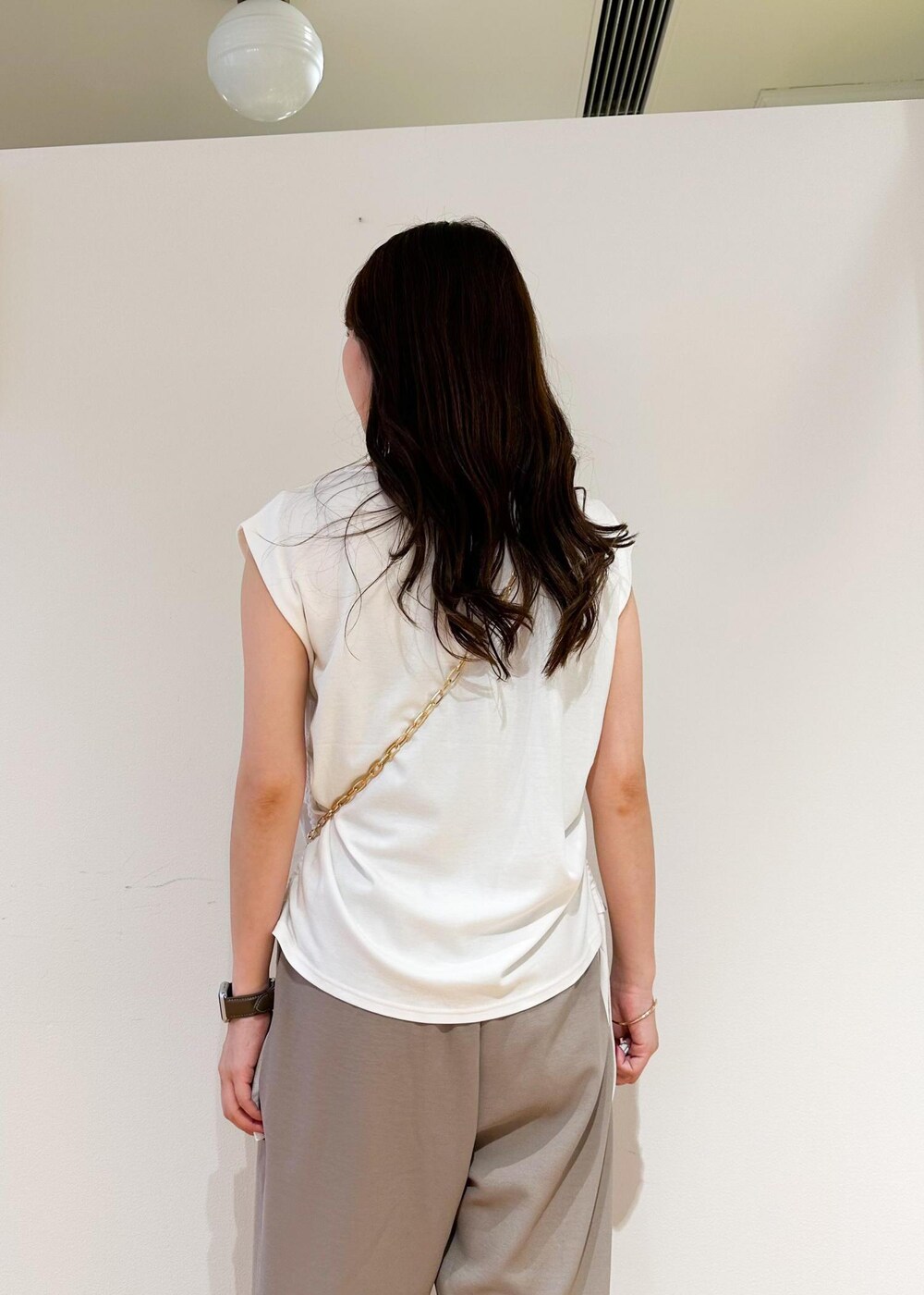 ブラック系のショルダーバッグ、ベージュ系のその他パンツ、ホワイト系のTシャツ/カットソーを着用したレディースの夏コーディネートの5枚目の写真