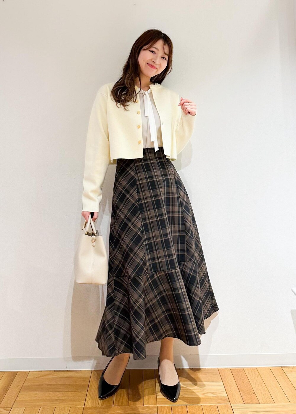 イエロー系のスカート、ベージュ系のシャツ/ブラウス、ホワイト系のカーディガン/ボレロを着用したレディースの冬コーディネートの2枚目の写真