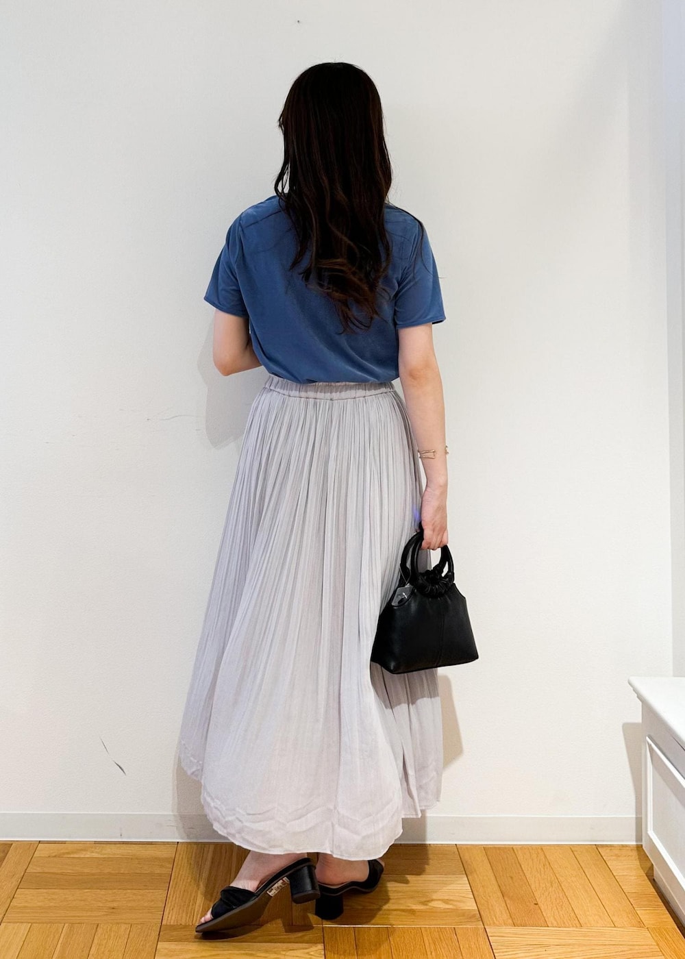 グレー系のスカート、ブラック系のショルダーバッグ、ブルー系のTシャツ/カットソーを着用したレディースの夏コーディネートの3枚目の写真