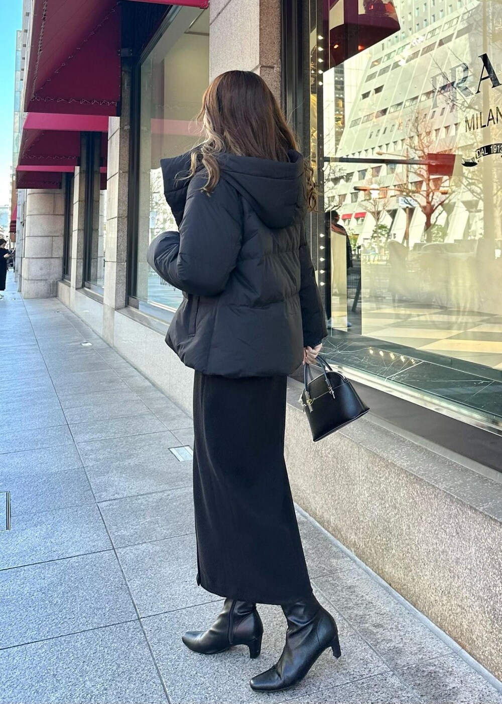 ブルー系のニット/セーター、ブラック系のダウンジャケット/コート、ブラック系のショルダーバッグを着用したレディースの冬コーディネートの3枚目の写真