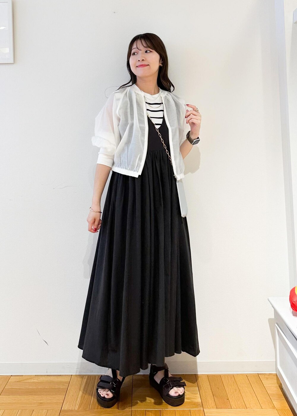 シルバー系のショルダーバッグ、ホワイト系のニット/セーター、ホワイト系のブルゾンを着用したレディースの夏コーディネートの2枚目の写真