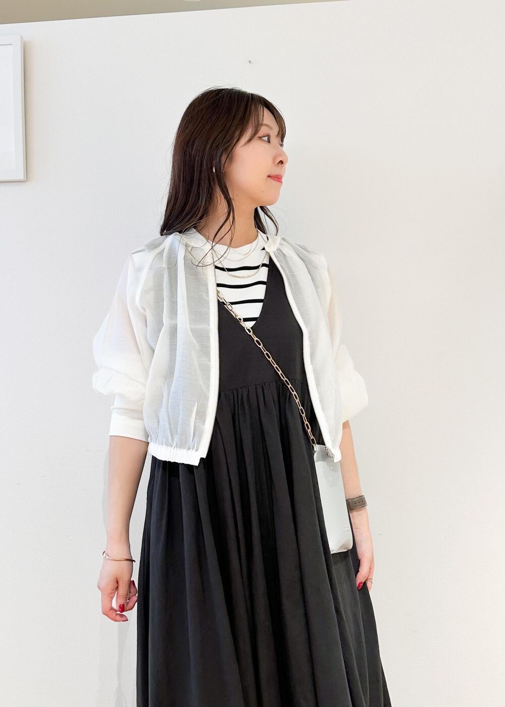 シルバー系のショルダーバッグ、ホワイト系のニット/セーター、ホワイト系のブルゾンを着用したレディースの夏コーディネートの4枚目の写真