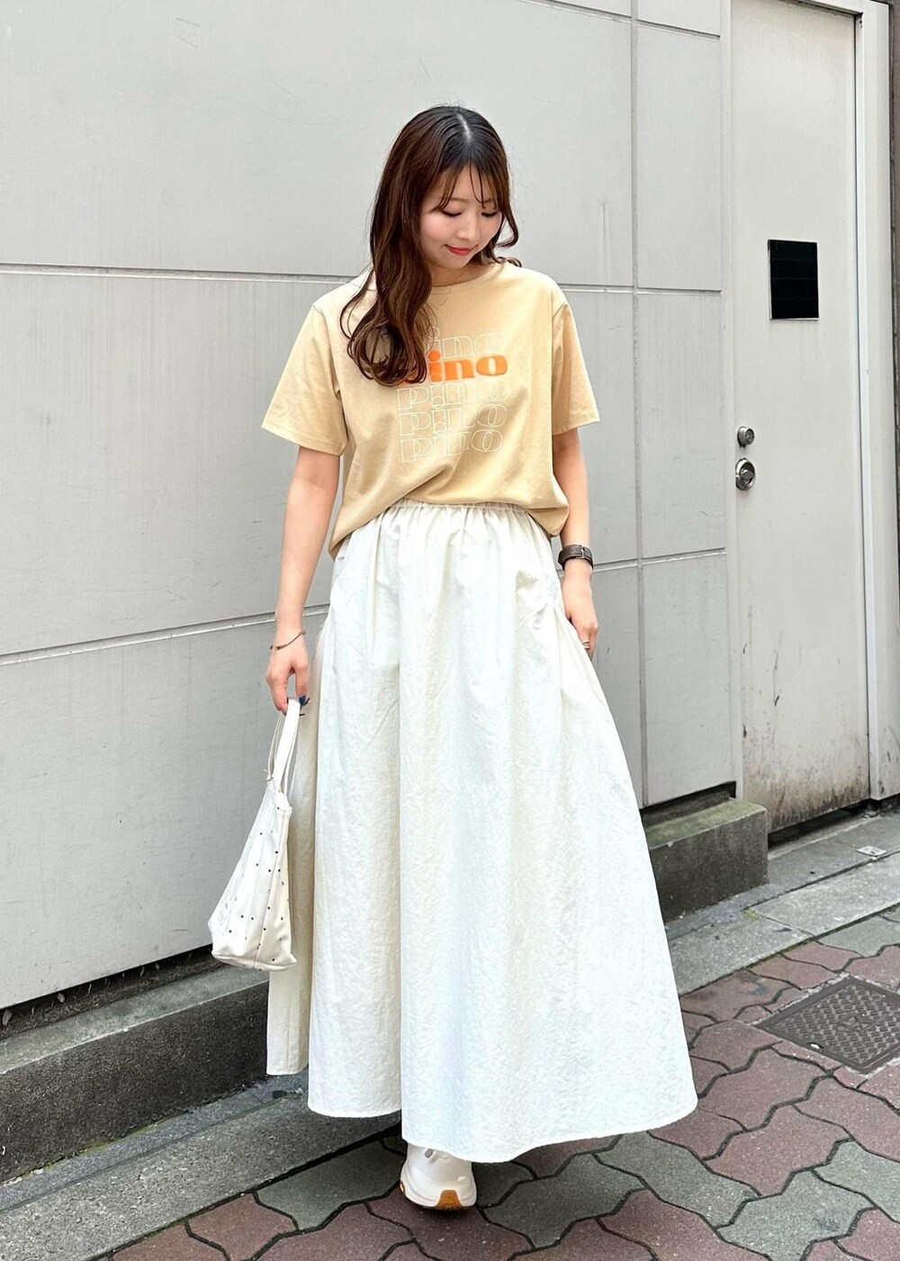 ベージュ系のTシャツ/カットソー、ホワイト系のスカート、ホワイト系のトートバッグを着用したレディースの春コーディネートの2枚目の写真