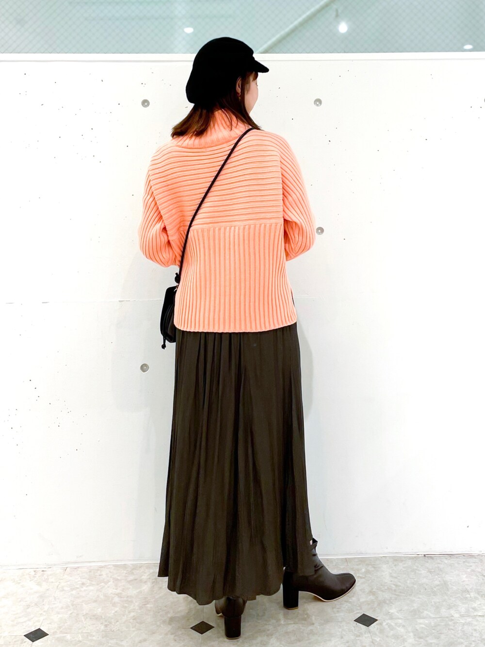 ピンク系のニット/セーター、グレー系のスカート、ブラック系のブーツを着用したレディースの冬コーディネートの2枚目の写真