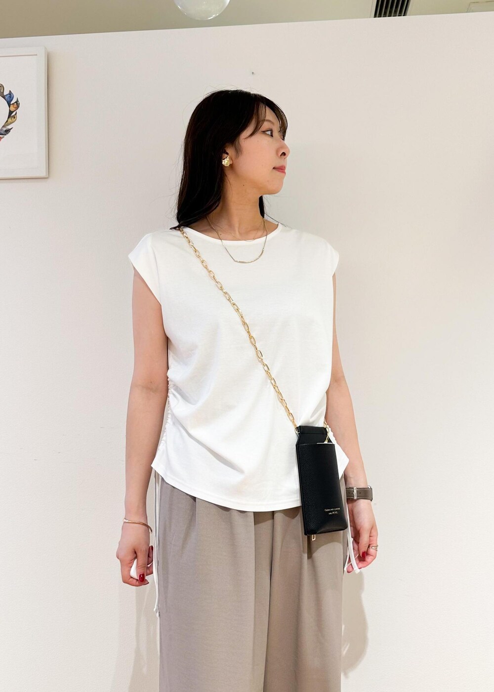 ブラック系のショルダーバッグ、ベージュ系のその他パンツ、ホワイト系のTシャツ/カットソーを着用したレディースの夏コーディネートの4枚目の写真