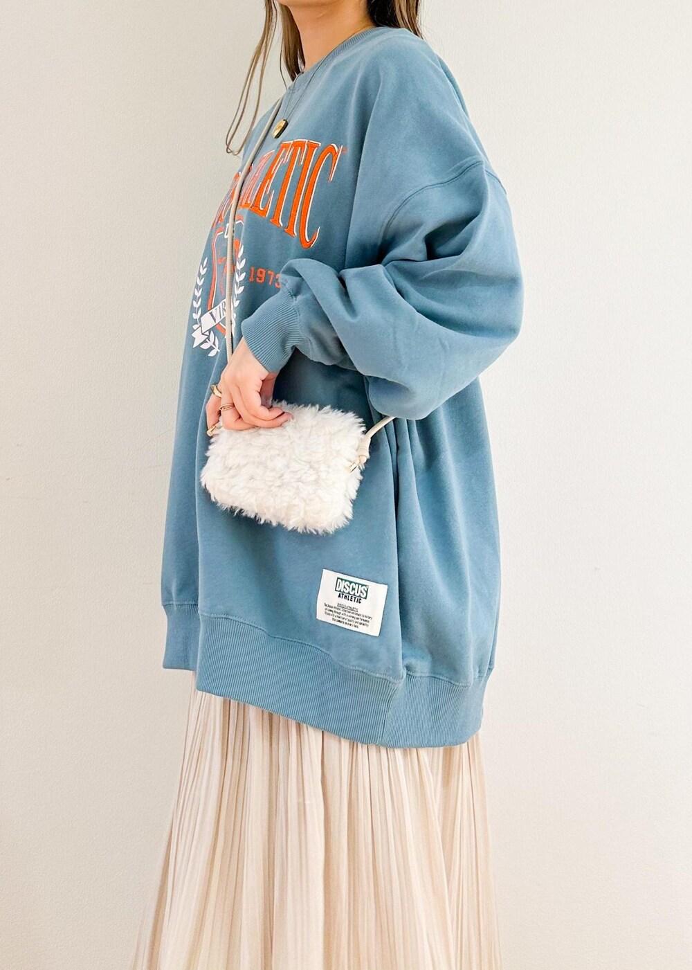 ベージュ系のスカート、ホワイト系のショルダーバッグ、グリーン系のスウェットを着用したレディースの秋コーディネートの6枚目の写真