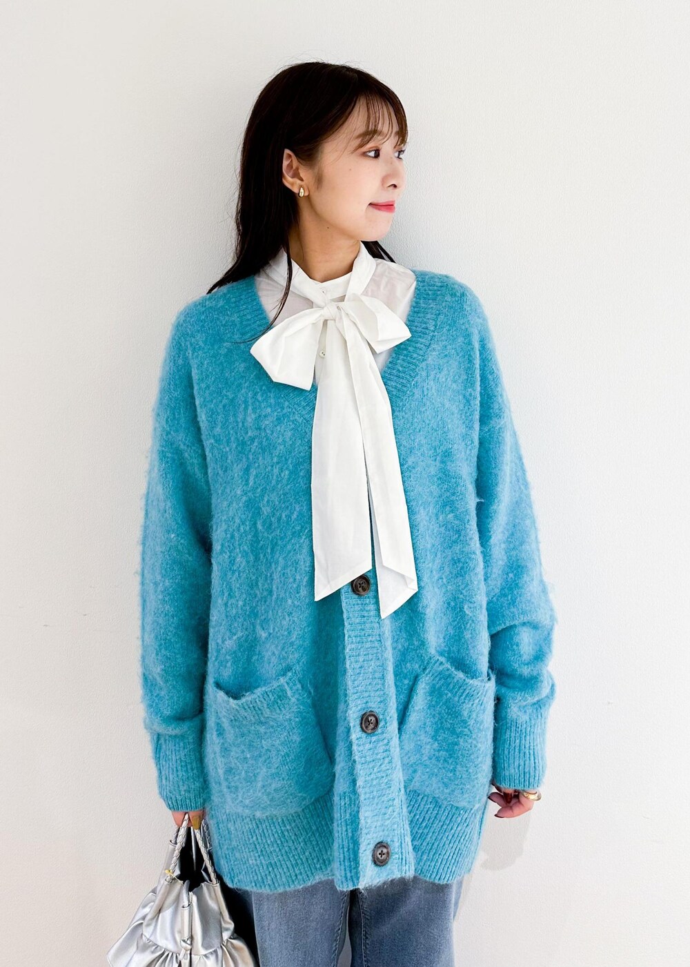 シルバー系のトートバッグ、ホワイト系のシャツ/ブラウス、グリーン系のカーディガン/ボレロを着用したレディースの秋コーディネートの4枚目の写真