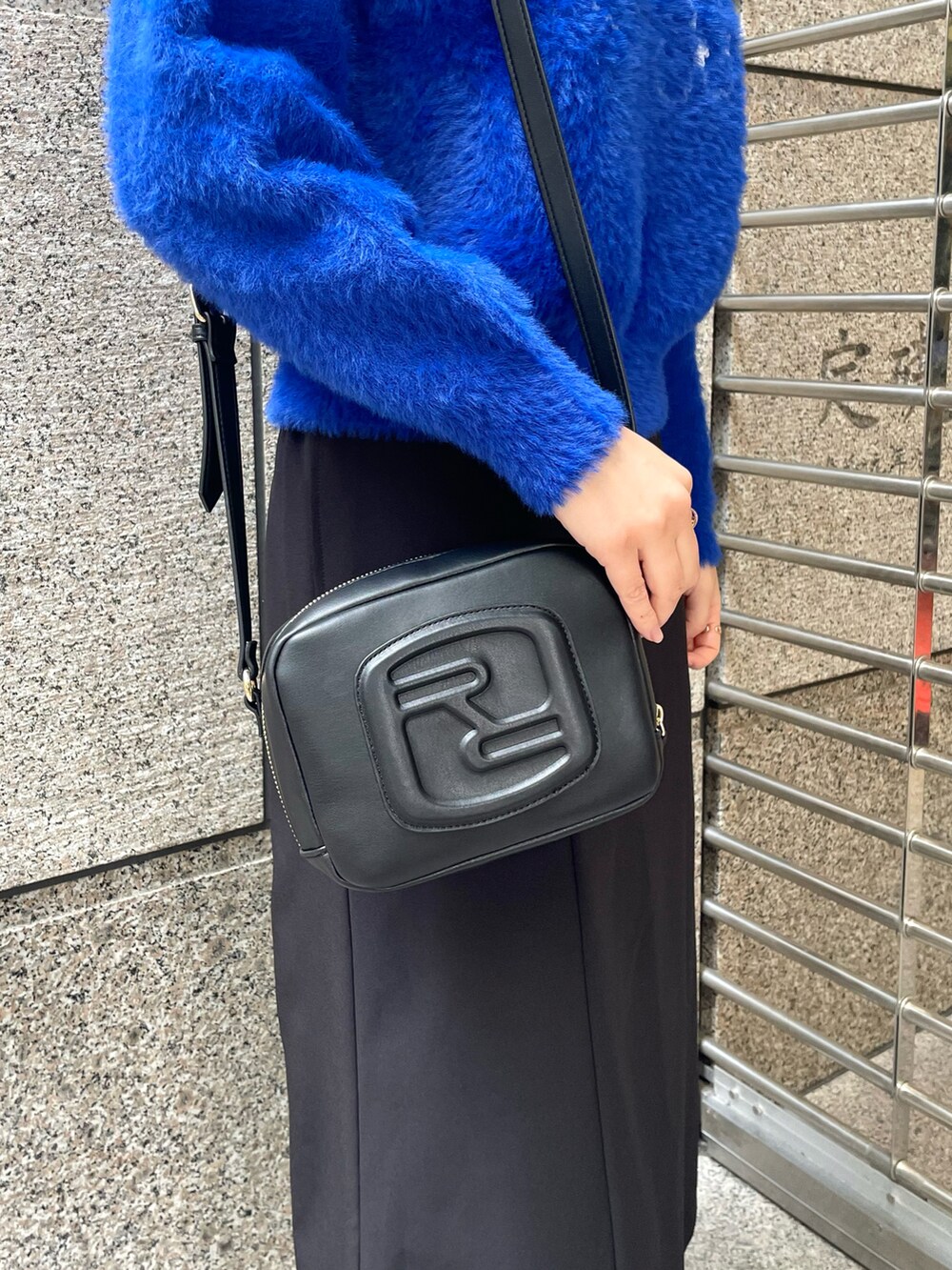 ブルー系のニット/セーター、ブラック系のスカート、ブラック系のショルダーバッグを着用したレディースの冬コーディネートの4枚目の写真