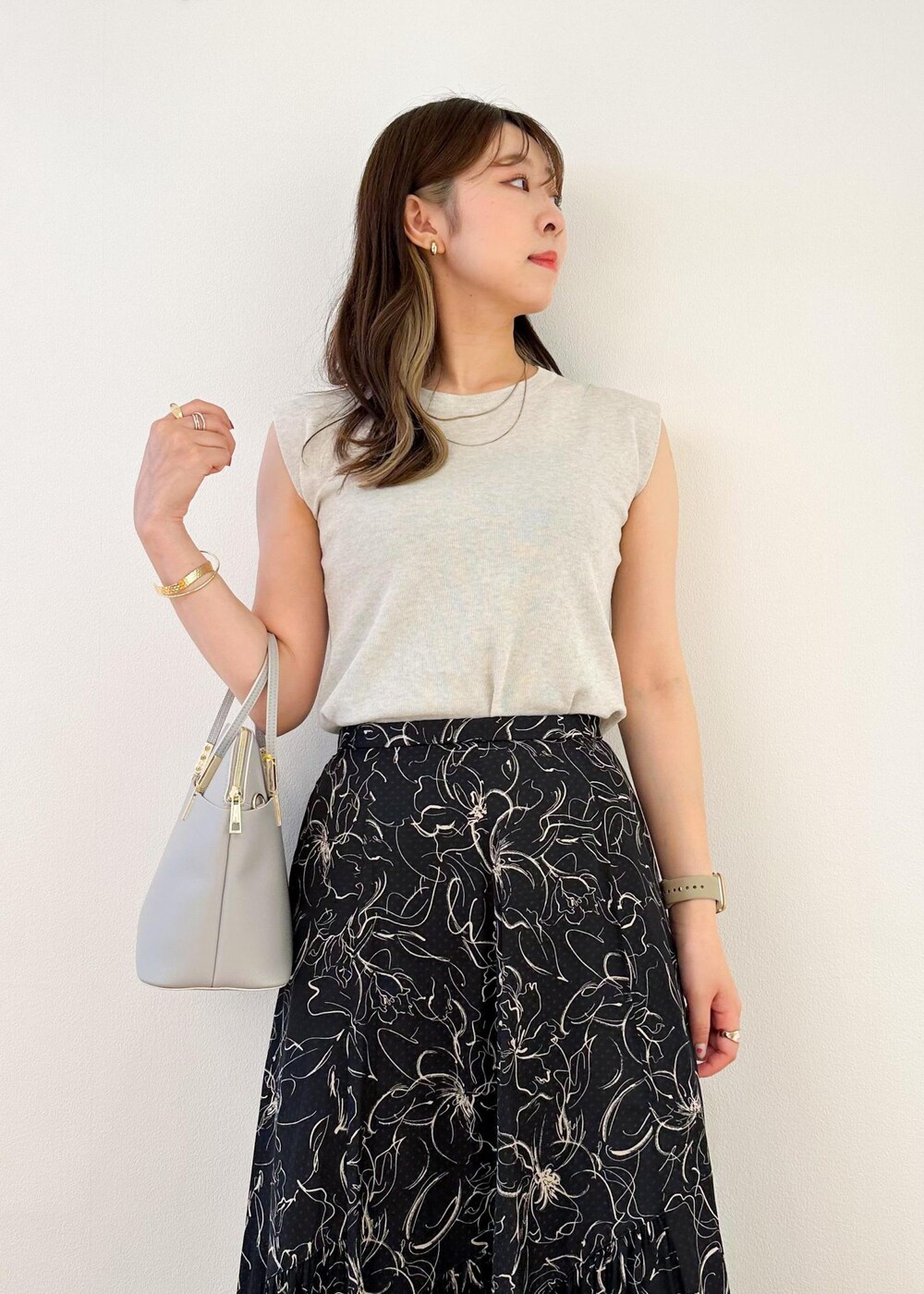 グレー系のニット/セーター、グレー系のショルダーバッグ、ブラック系のスカートを着用したレディースの夏コーディネートの4枚目の写真