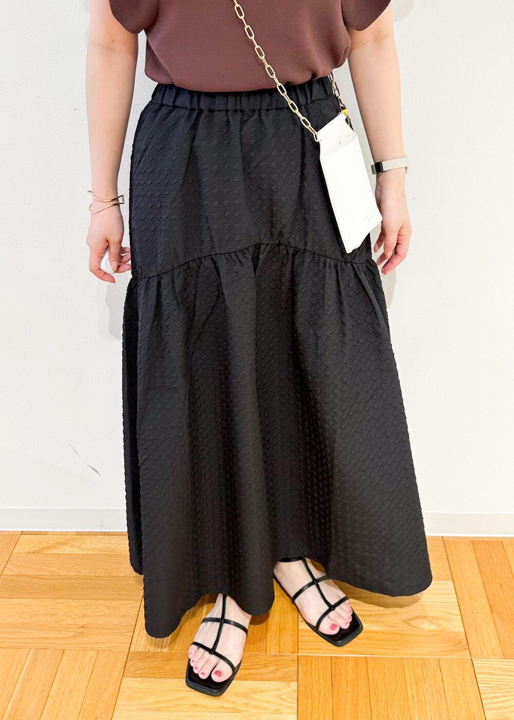 ホワイト系のショルダーバッグ、ブラウン系のニット/セーター、ブラック系のスカートを着用したレディースの夏コーディネートの7枚目の写真