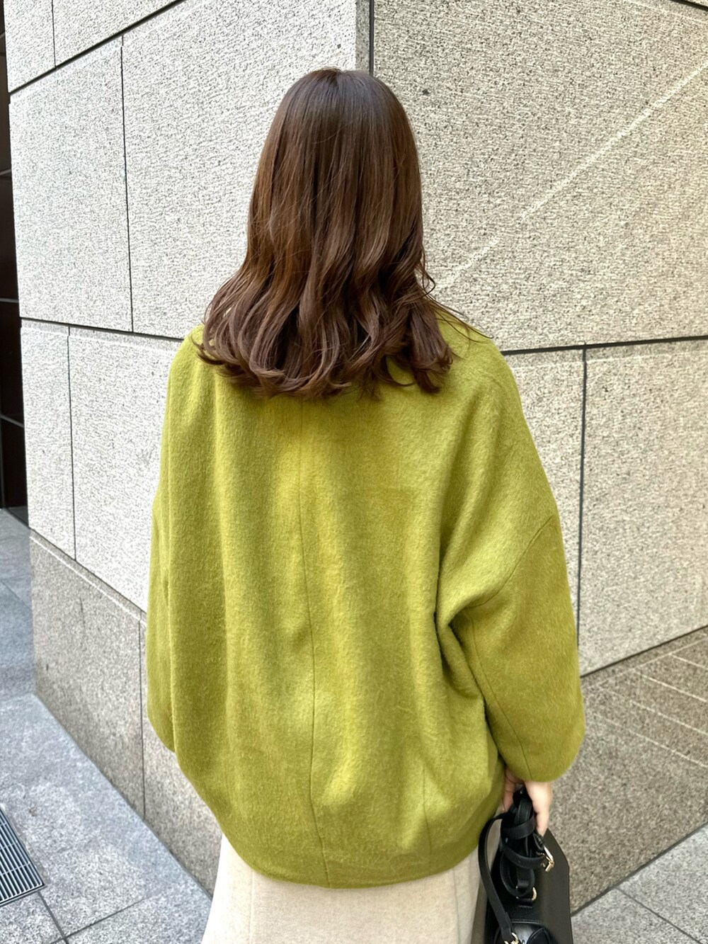 イエロー系のその他アウター、ベージュ系のスカート、ホワイト系のニット/セーターを着用したレディースの冬コーディネートの4枚目の写真