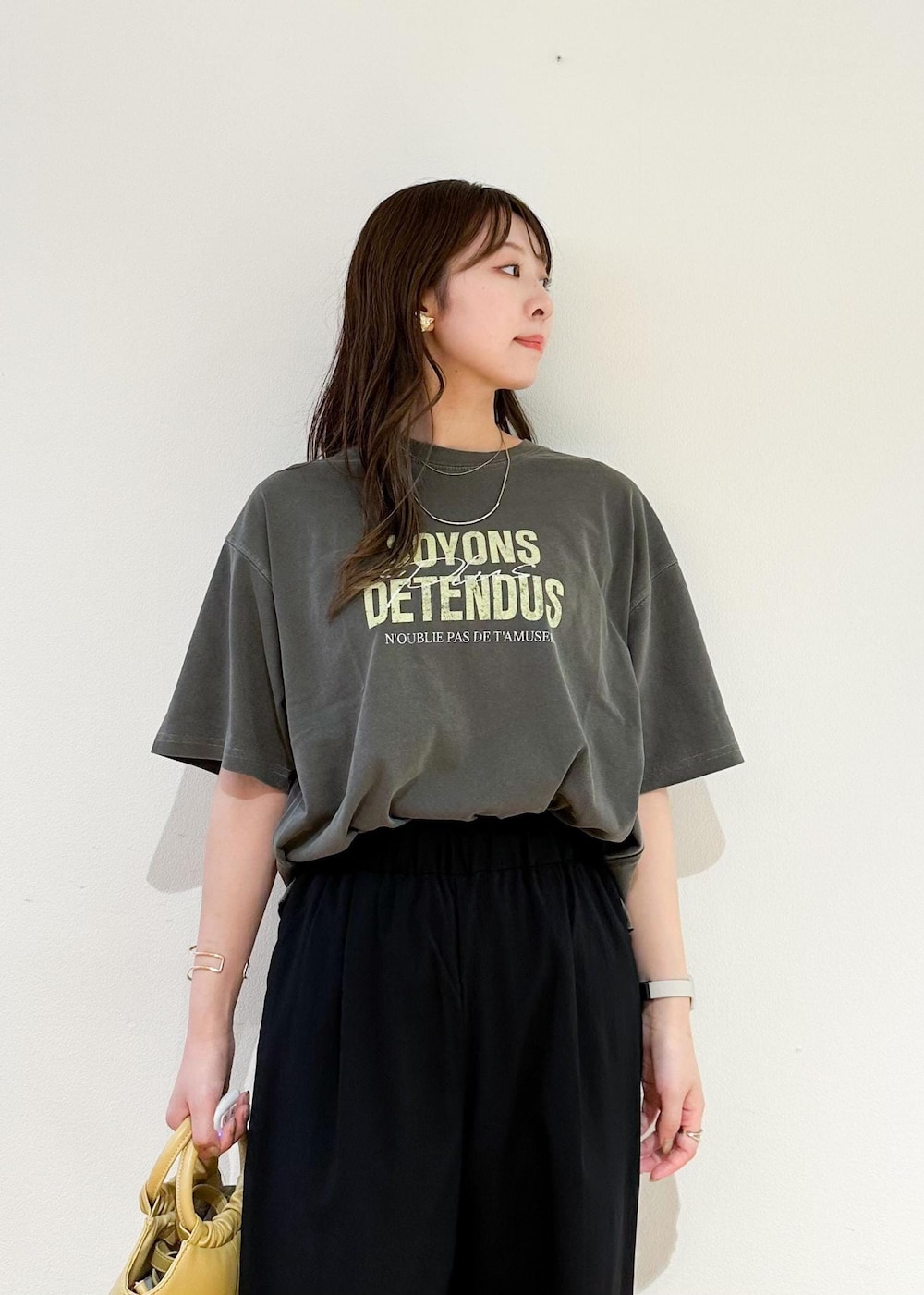 イエロー系のショルダーバッグ、グレー系のTシャツ/カットソー、ブラック系のその他パンツを着用したレディースの秋コーディネートの5枚目の写真