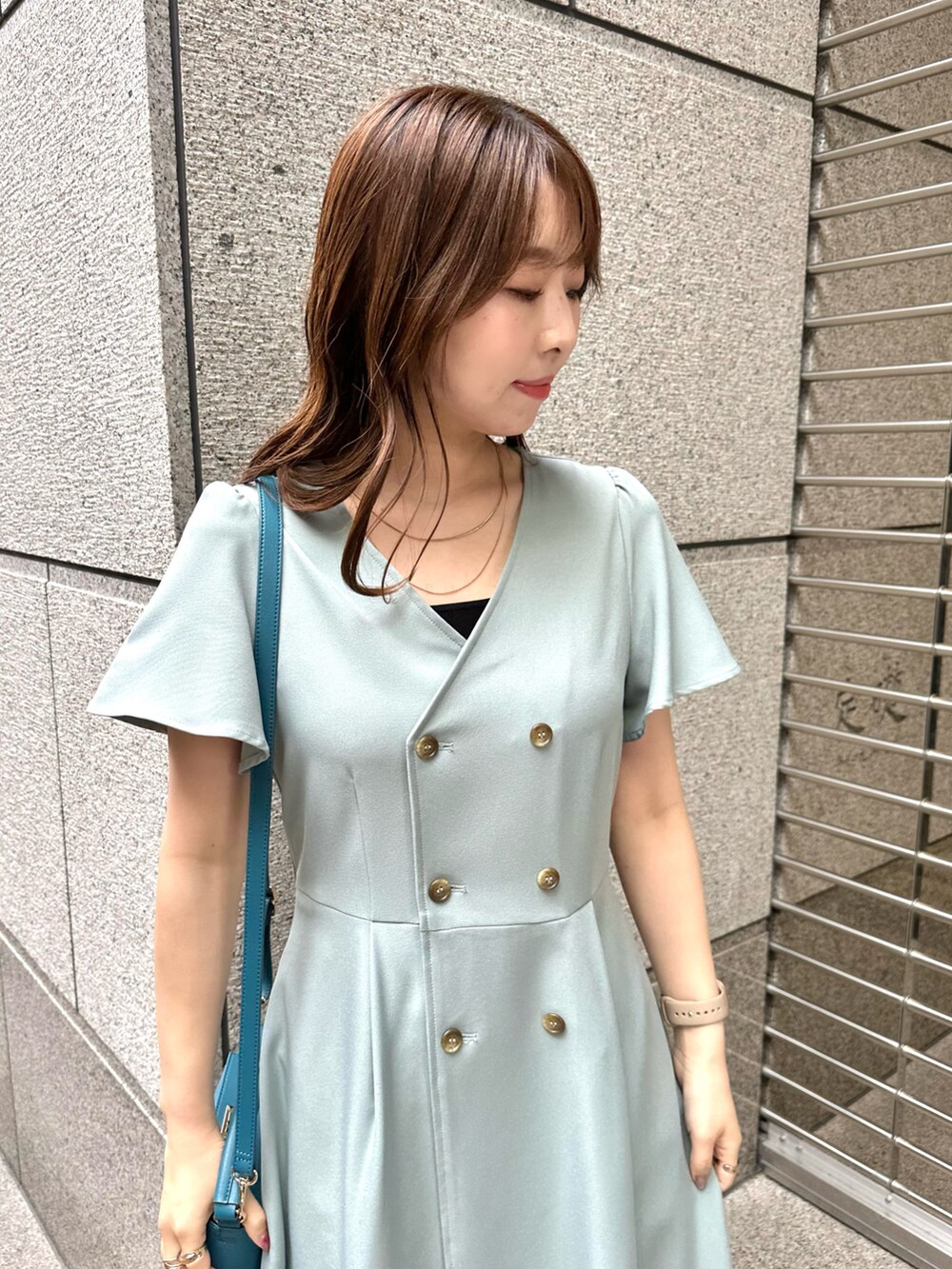 グリーン系のワンピース、ブルー系のショルダーバッグを着用したレディースの春コーディネートの3枚目の写真