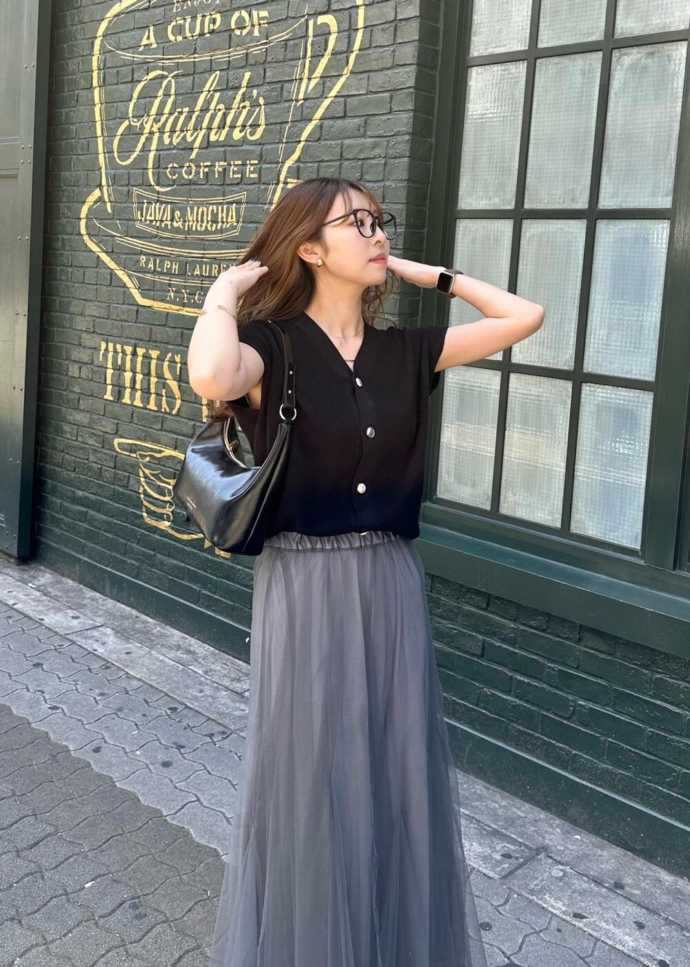 グレー系のスカート、ブラック系のニット/セーター、ブラック系のショルダーバッグを着用したレディースの春コーディネートの5枚目の写真