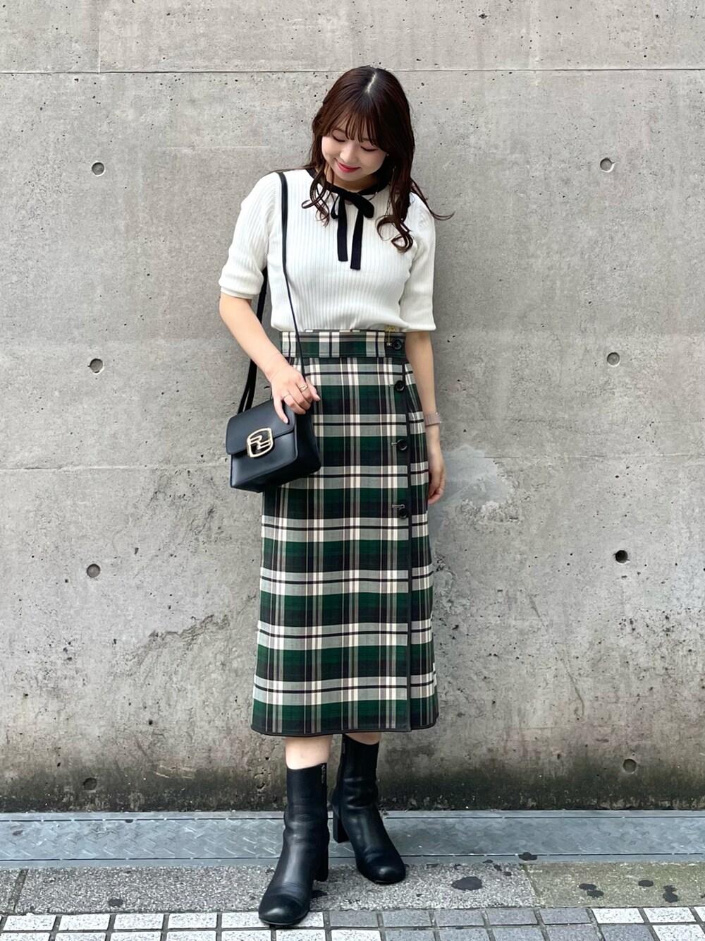 グリーン系のスカート、ブラック系のショルダーバッグ、ホワイト系のニット/セーターを着用したレディースの秋コーディネートの3枚目の写真