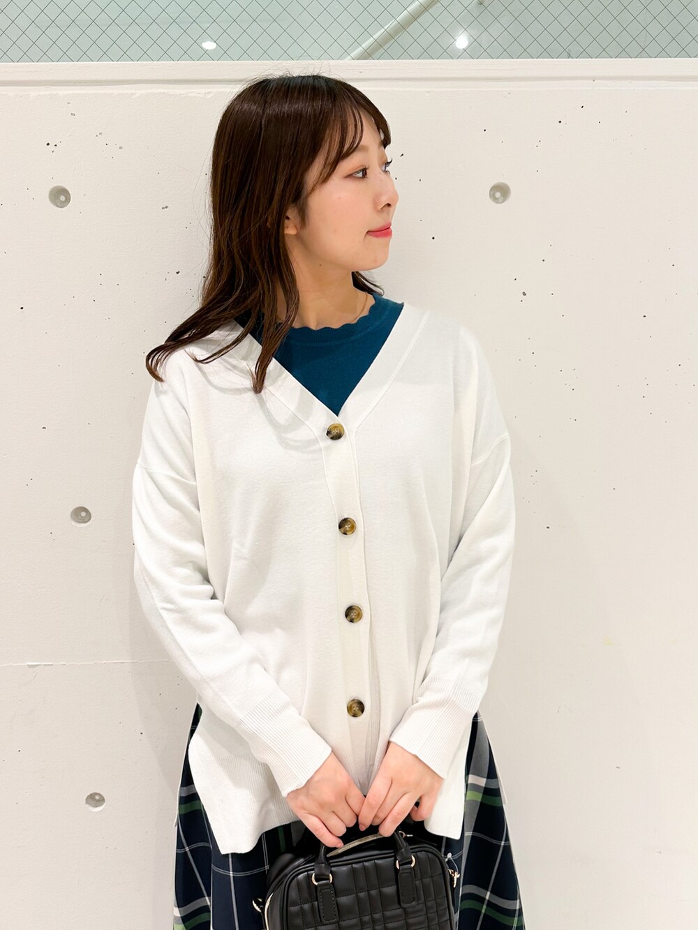 ホワイト系のカーディガン/ボレロ、グリーン系のニット/セーター、ホワイト系のスカートを着用したレディースの冬コーディネートの3枚目の写真