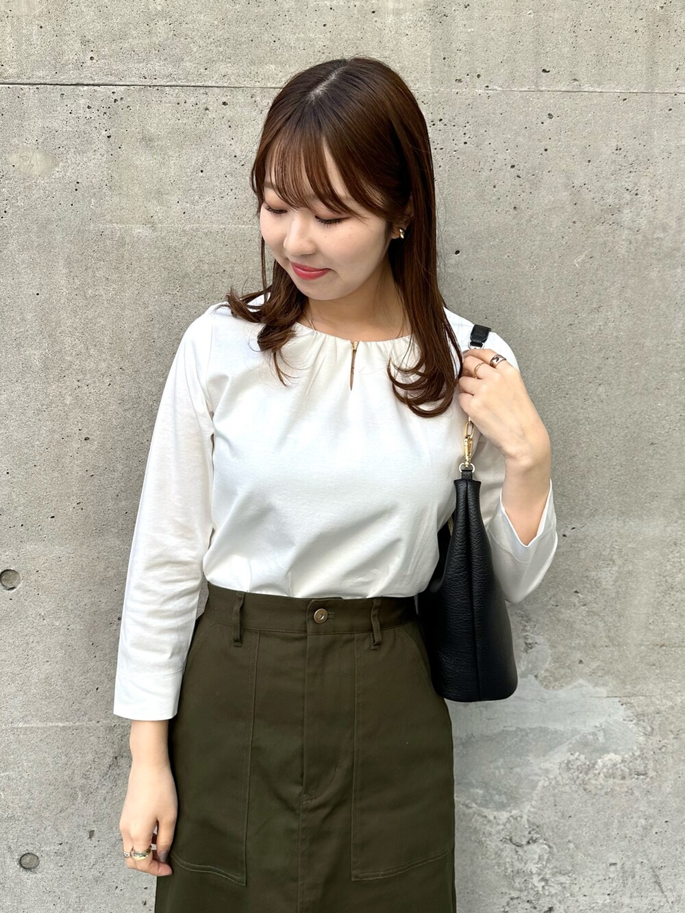 ホワイト系のTシャツ/カットソー、グリーン系のスカート、ブラック系のショルダーバッグを着用したレディースの春コーディネートの3枚目の写真