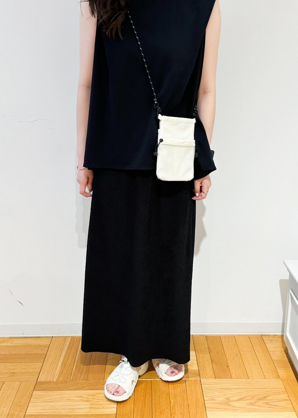 ホワイト系のショルダーバッグ、ブラック系のスカート、ホワイト系のサンダルを着用したレディースの春コーディネートの7枚目の写真