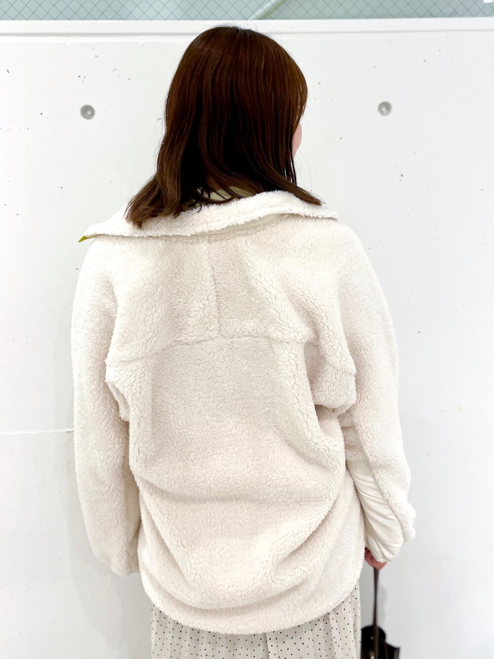 ホワイト系のブルゾン、ホワイト系のスカート、イエロー系のニット/セーターを着用したレディースの冬コーディネートの4枚目の写真