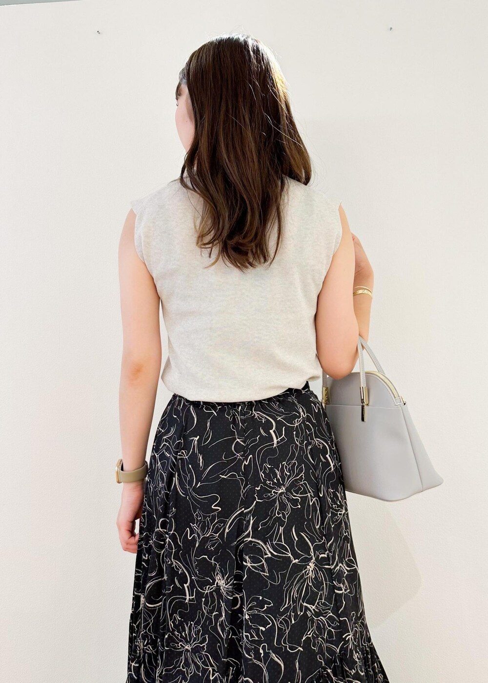 グレー系のニット/セーター、グレー系のショルダーバッグ、ブラック系のスカートを着用したレディースの夏コーディネートの5枚目の写真