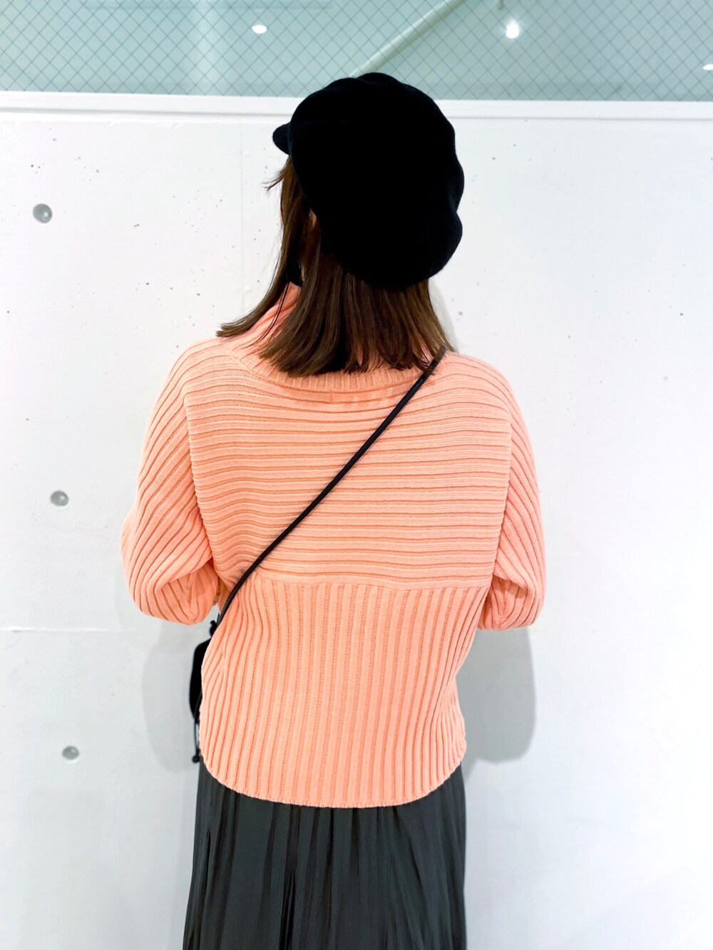 ピンク系のニット/セーター、グレー系のスカート、ブラック系のブーツを着用したレディースの冬コーディネートの4枚目の写真