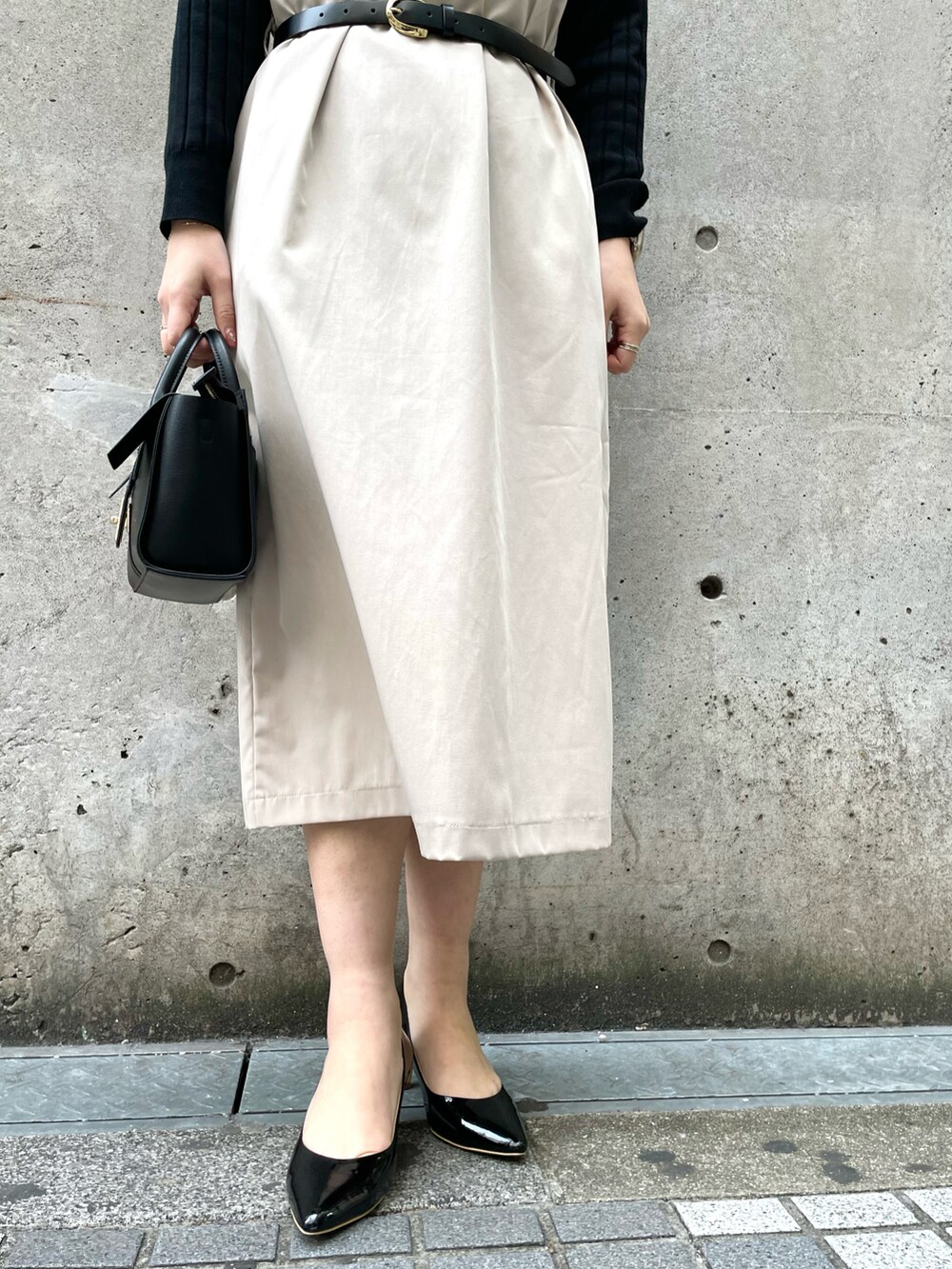ベージュ系のジャンパースカート、ブラック系のショルダーバッグ、ブラック系のパンプスを着用したレディースの春コーディネートの5枚目の写真