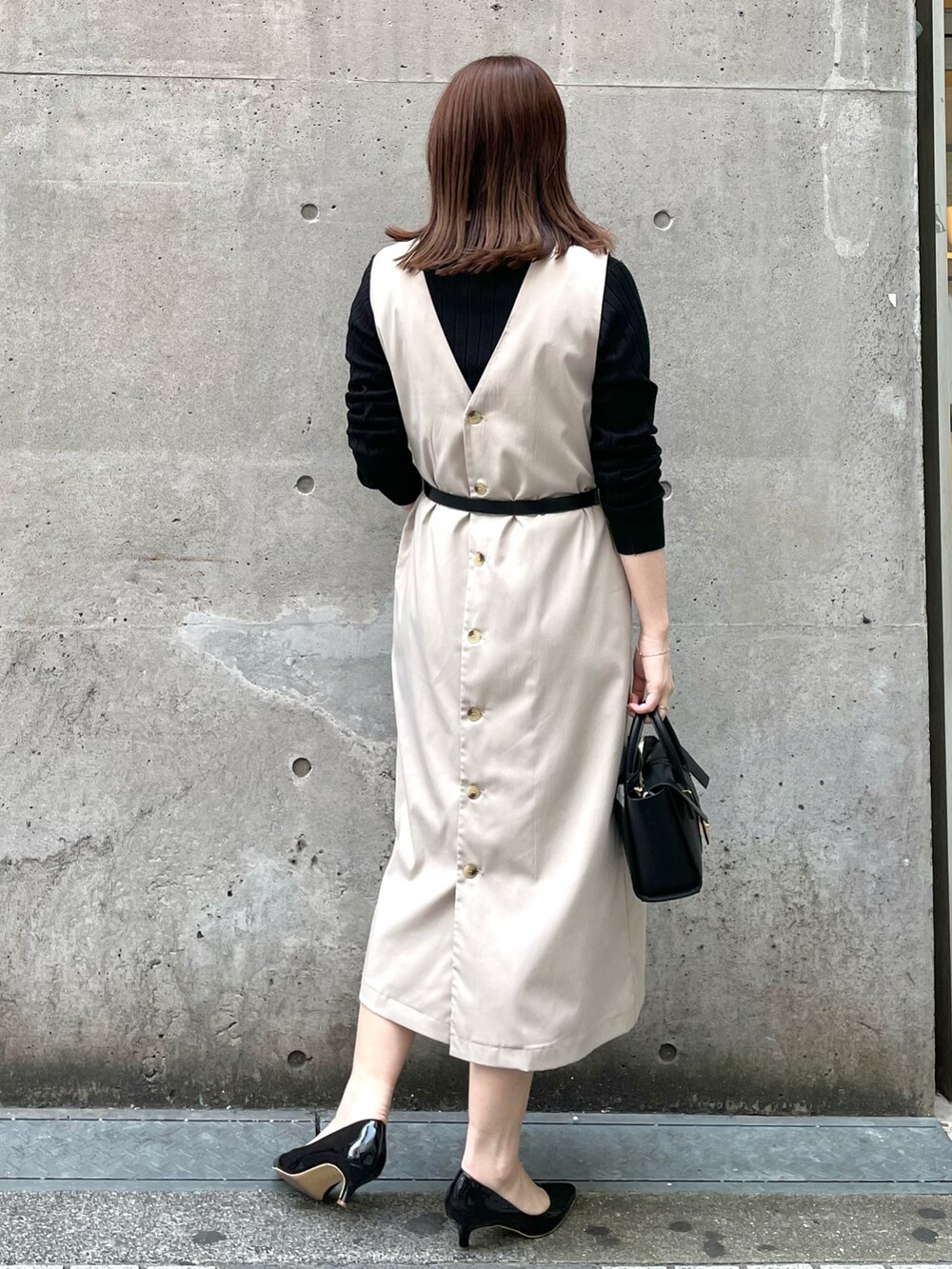 ベージュ系のジャンパースカート、ブラック系のショルダーバッグ、ブラック系のパンプスを着用したレディースの春コーディネートの2枚目の写真