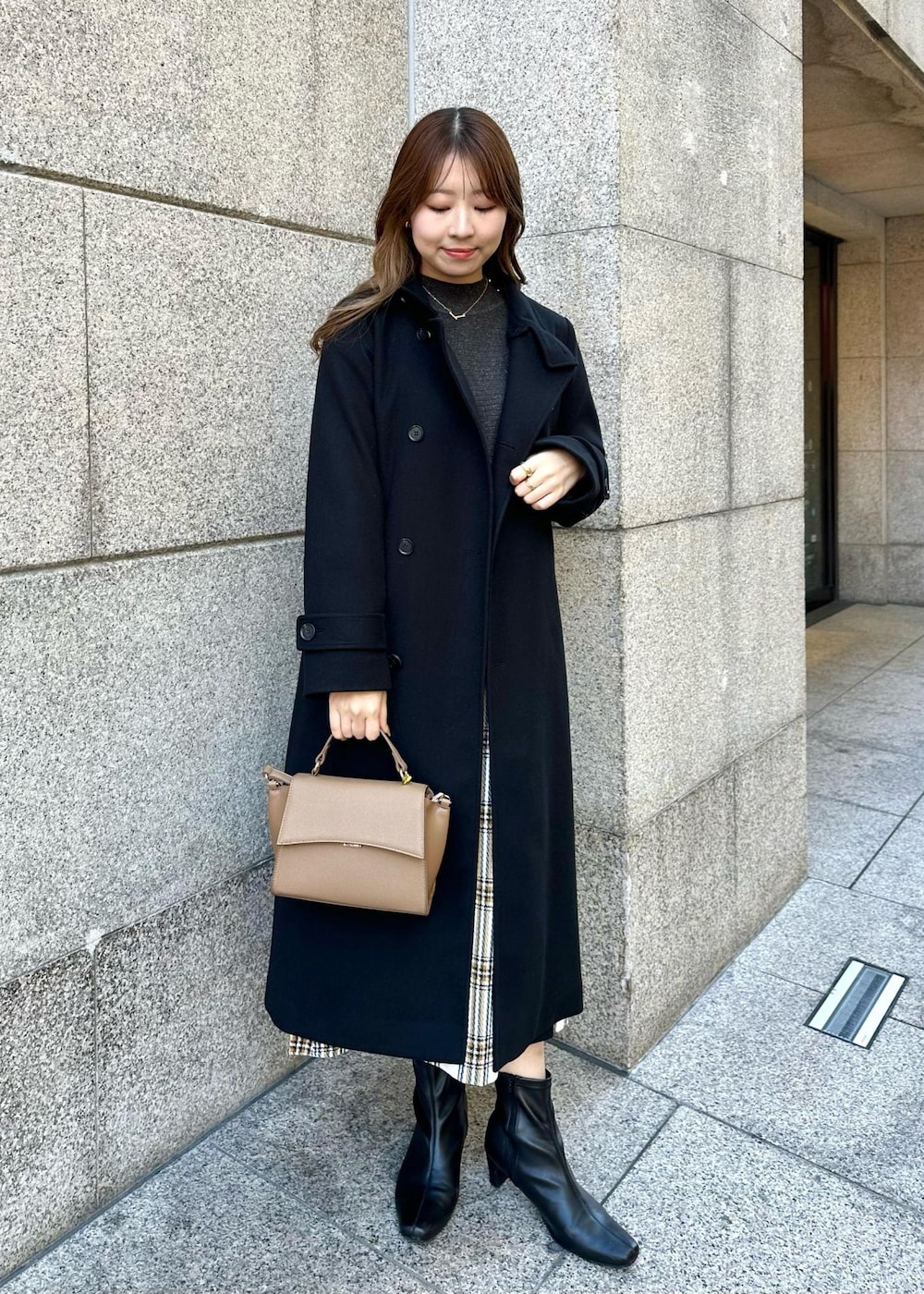 ブラウン系のショルダーバッグ、ブラック系のその他アウター、ホワイト系のスカートを着用したレディースの冬コーディネートの2枚目の写真