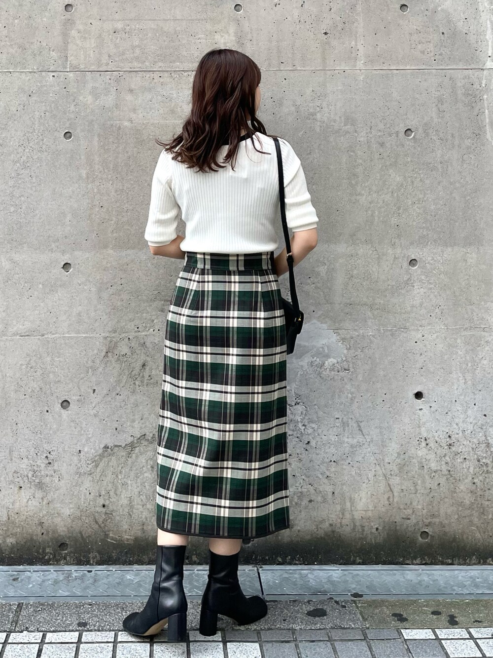 グリーン系のスカート、ブラック系のショルダーバッグ、ホワイト系のニット/セーターを着用したレディースの秋コーディネートの4枚目の写真