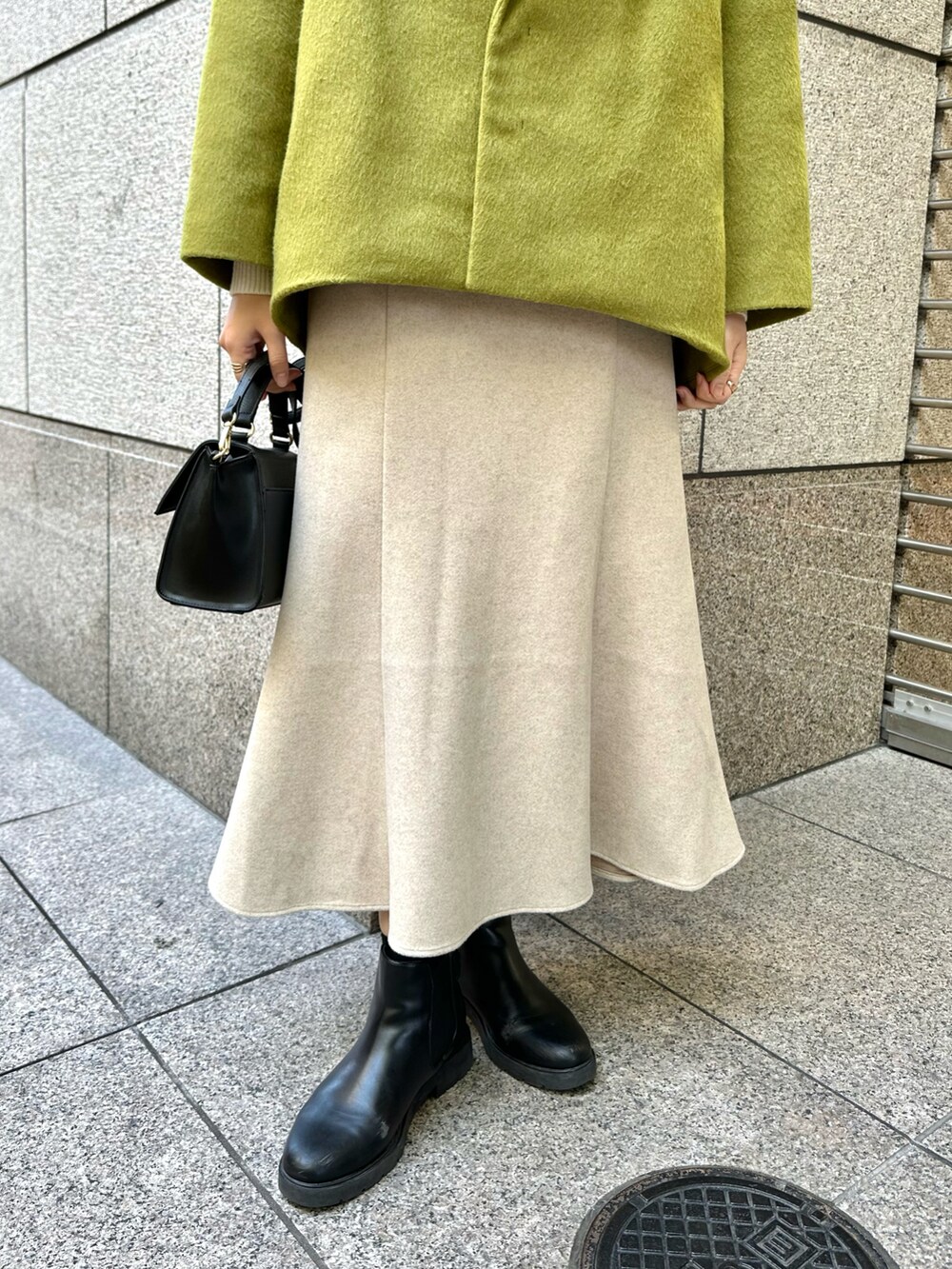 イエロー系のその他アウター、ベージュ系のスカート、ホワイト系のニット/セーターを着用したレディースの冬コーディネートの5枚目の写真