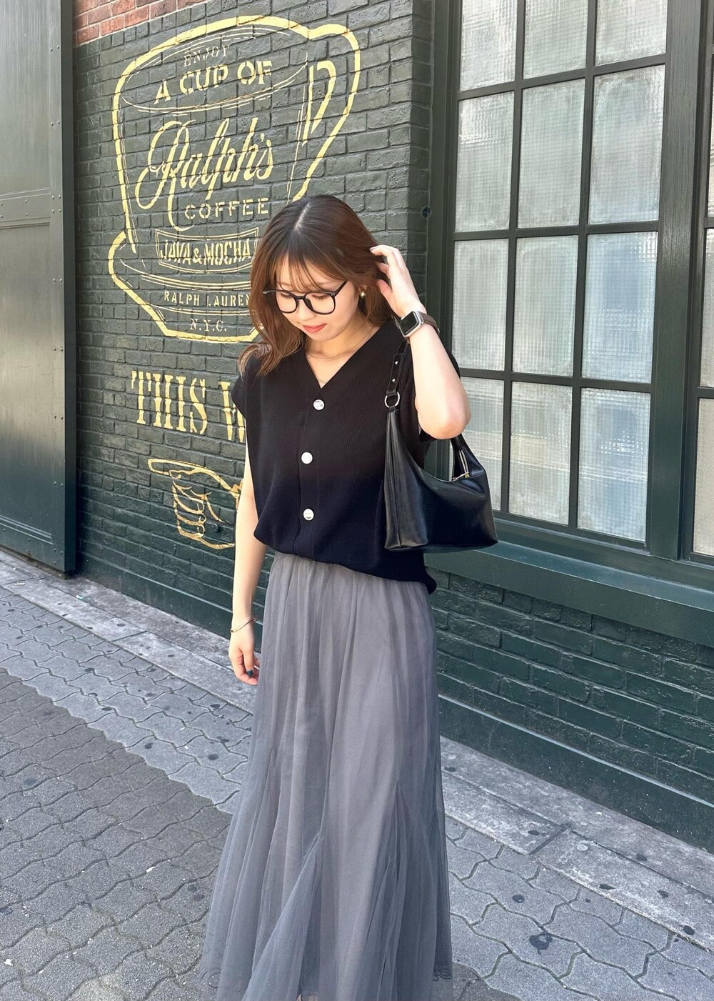 グレー系のスカート、ブラック系のニット/セーター、ブラック系のショルダーバッグを着用したレディースの春コーディネートの6枚目の写真