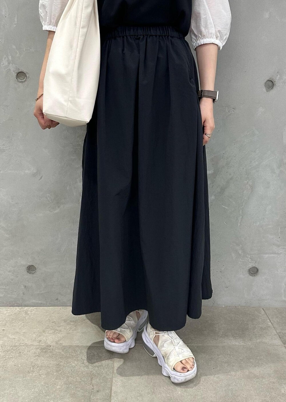 ホワイト系のトートバッグ、ブラック系のスカート、ブラック系のTシャツ/カットソーを着用したレディースの夏コーディネートの6枚目の写真