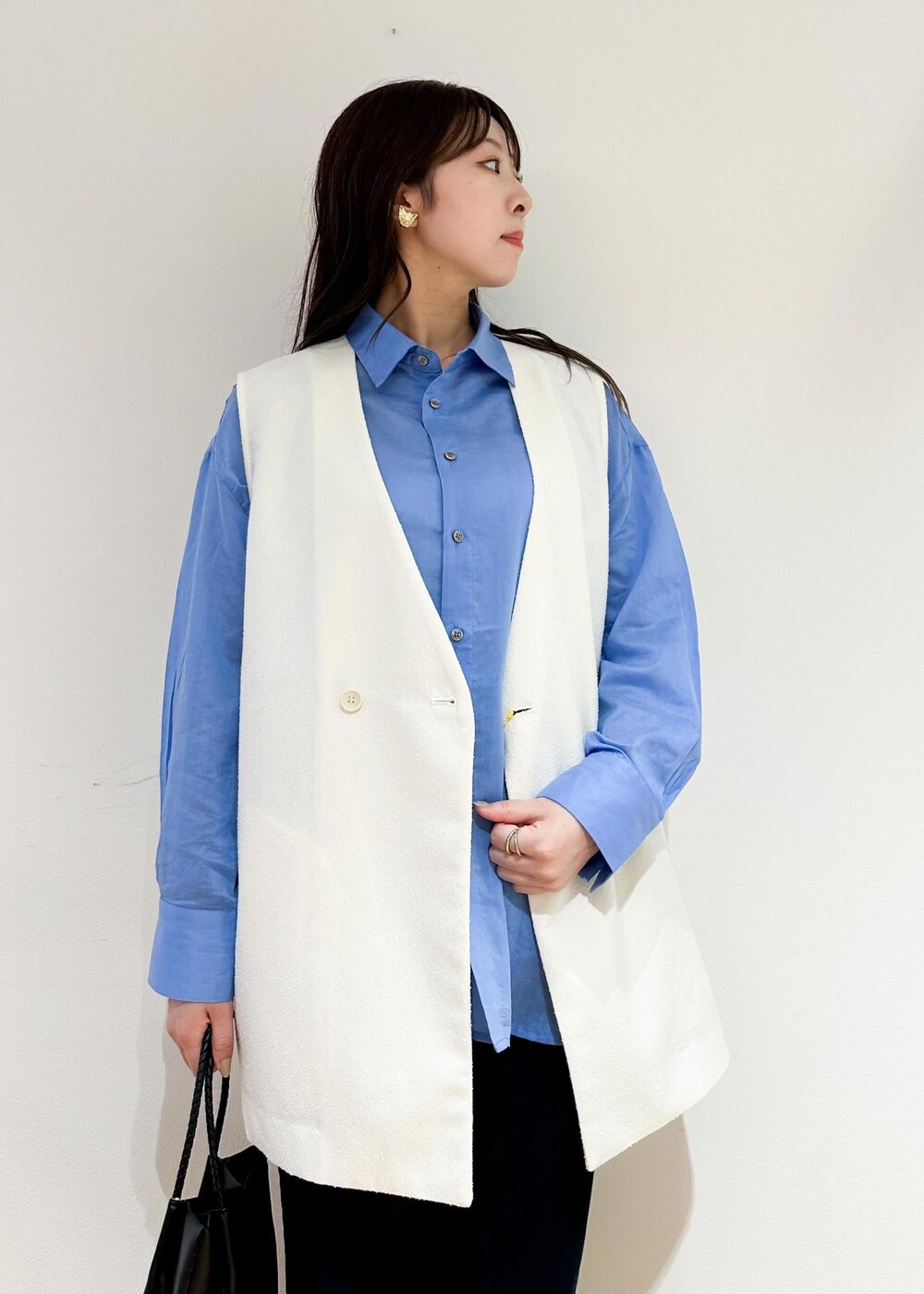 ブラック系のトートバッグ、ホワイト系のベスト、ブルー系のシャツ/ブラウスを着用したレディースの夏コーディネートの5枚目の写真