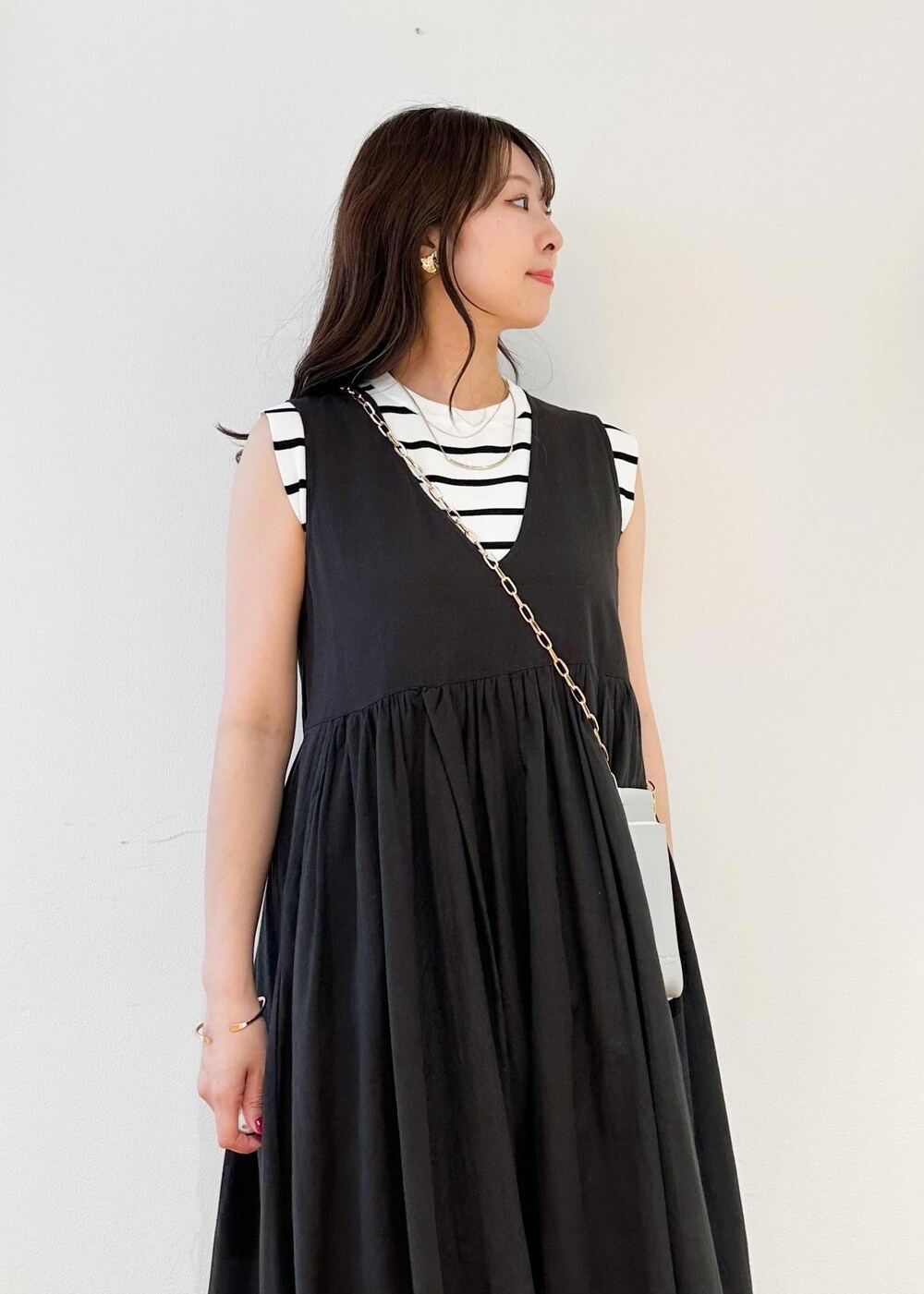 シルバー系のショルダーバッグ、ホワイト系のニット/セーター、ブラック系のワンピースを着用したレディースの夏コーディネートの3枚目の写真