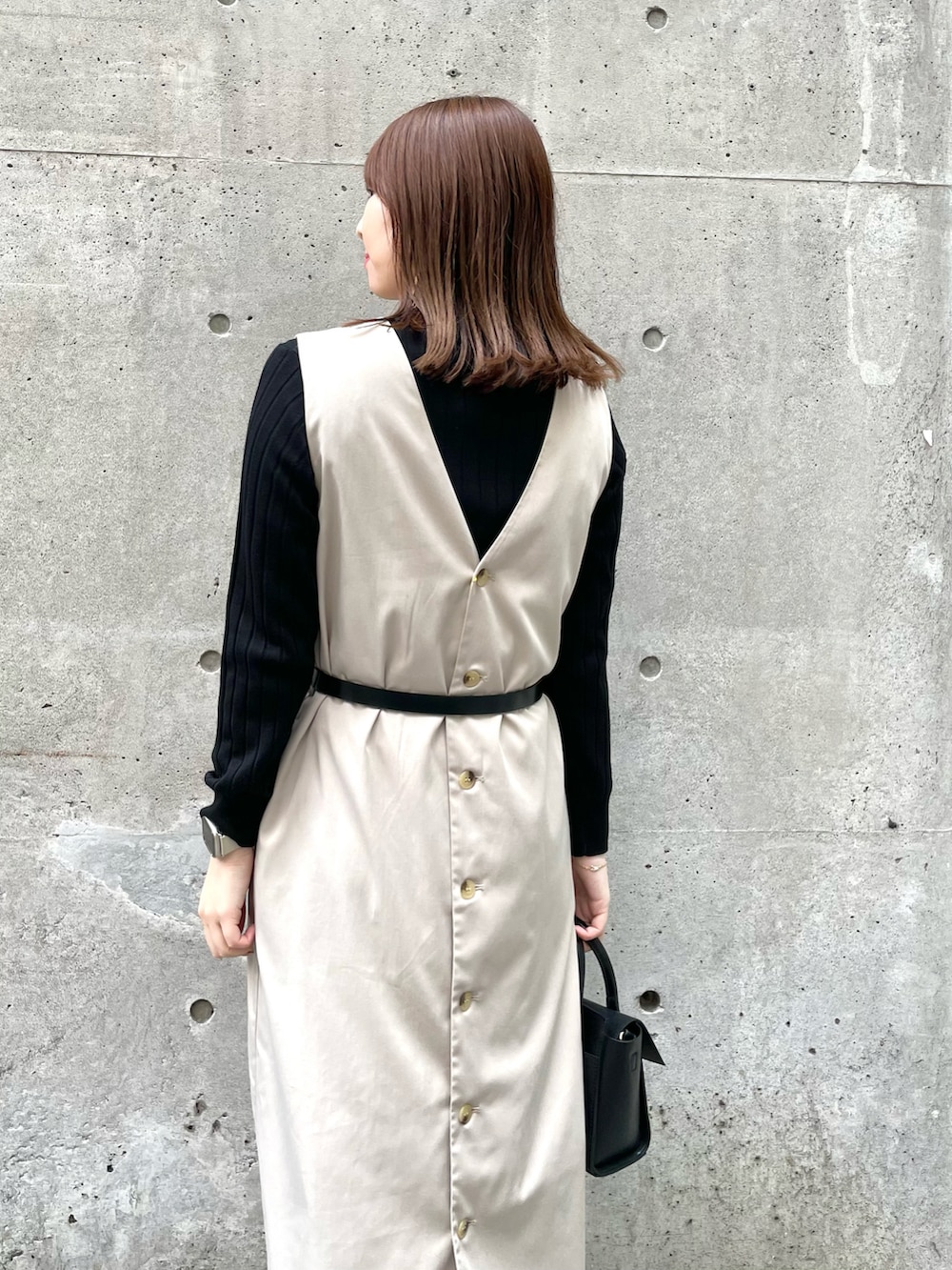 ベージュ系のジャンパースカート、ブラック系のショルダーバッグ、ブラック系のパンプスを着用したレディースの春コーディネートの4枚目の写真