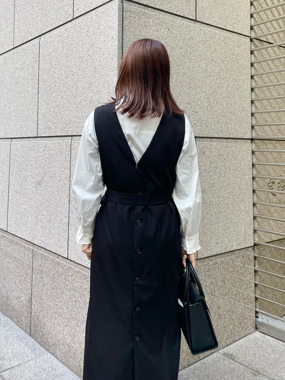 ホワイト系のシャツ/ブラウス、ブラック系のジャンパースカート、ブラック系のパンプスを着用したレディースの冬コーディネートの4枚目の写真