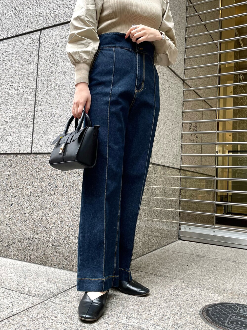 ベージュ系のニット/セーター、ブルー系のデニムパンツ、ブラック系のトートバッグを着用したレディースの春コーディネートの5枚目の写真
