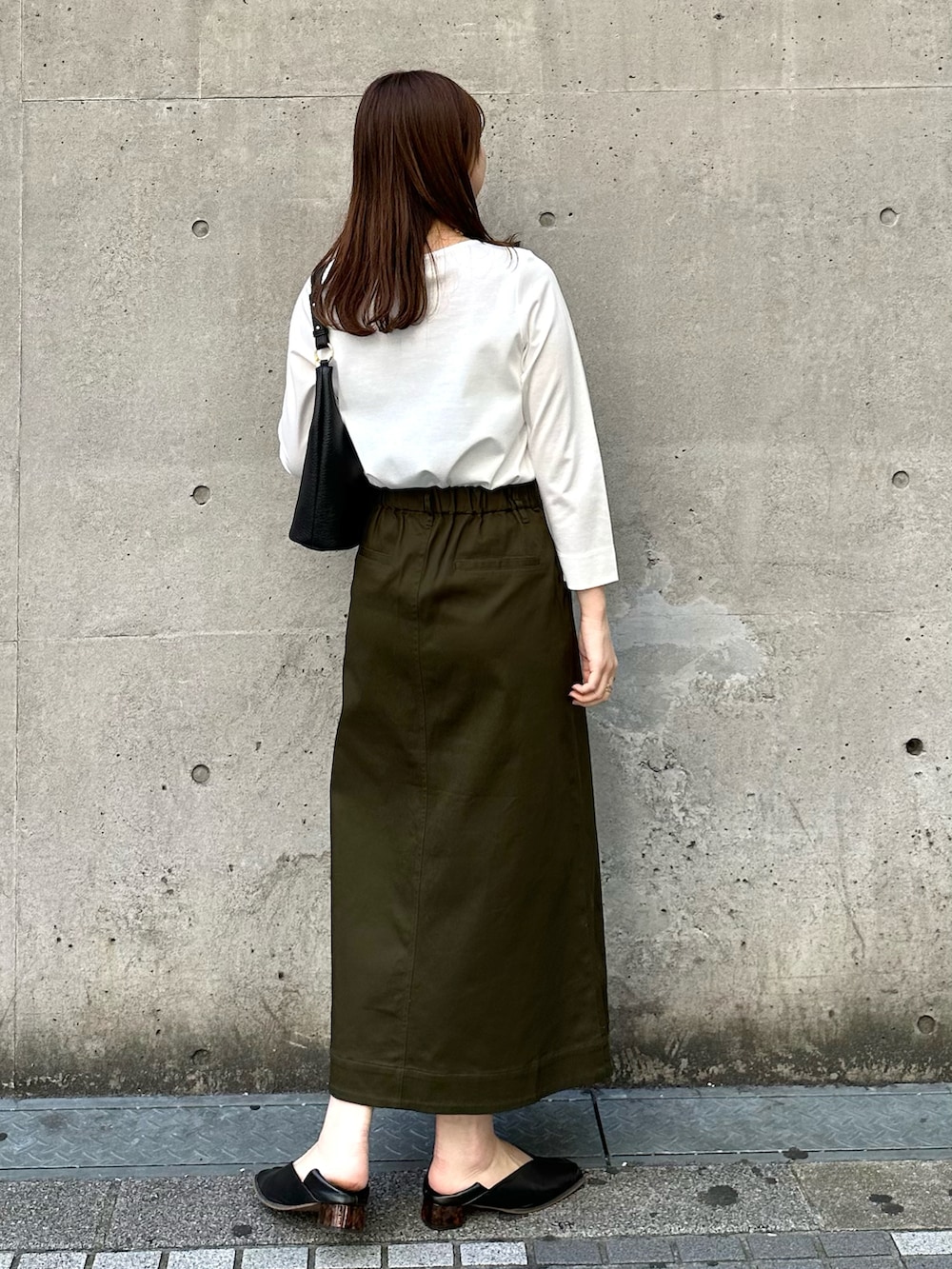 ホワイト系のTシャツ/カットソー、グリーン系のスカート、ブラック系のショルダーバッグを着用したレディースの春コーディネートの2枚目の写真