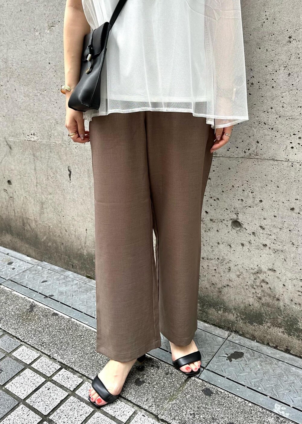 ブラック系のショルダーバッグ、ブラウン系のその他パンツ、ホワイト系のTシャツ/カットソーを着用したレディースの夏コーディネートの6枚目の写真
