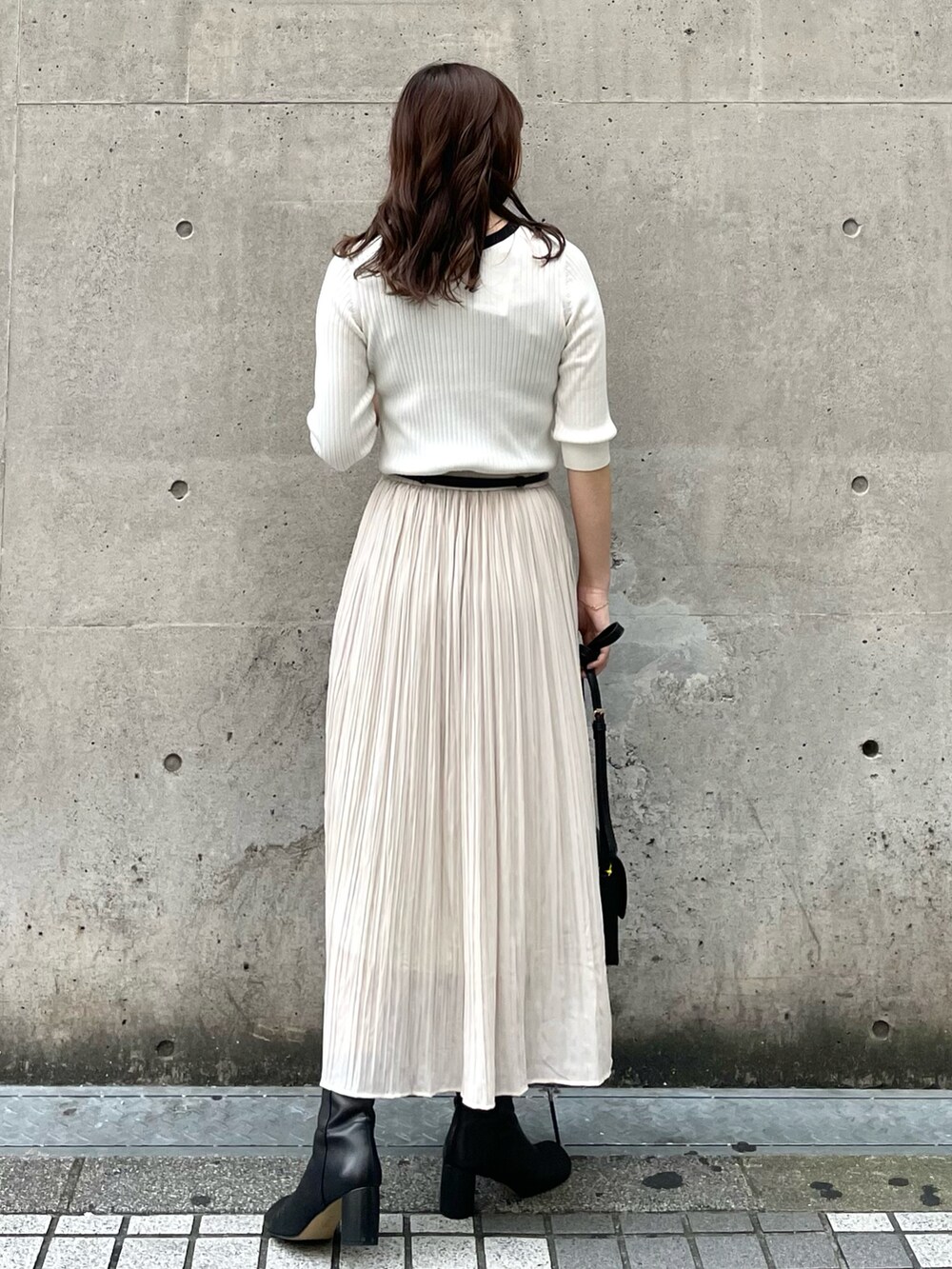 ブラック系のショルダーバッグ、ブラック系のベスト、ホワイト系のニット/セーターを着用したレディースの秋コーディネートの4枚目の写真