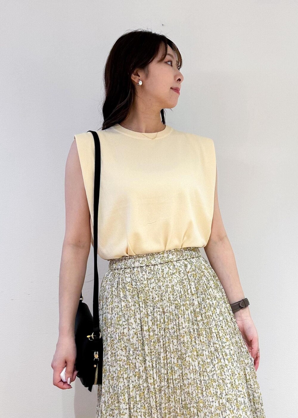 ベージュ系のニット/セーター、イエロー系のスカート、ブラック系のショルダーバッグを着用したレディースの春コーディネートの4枚目の写真