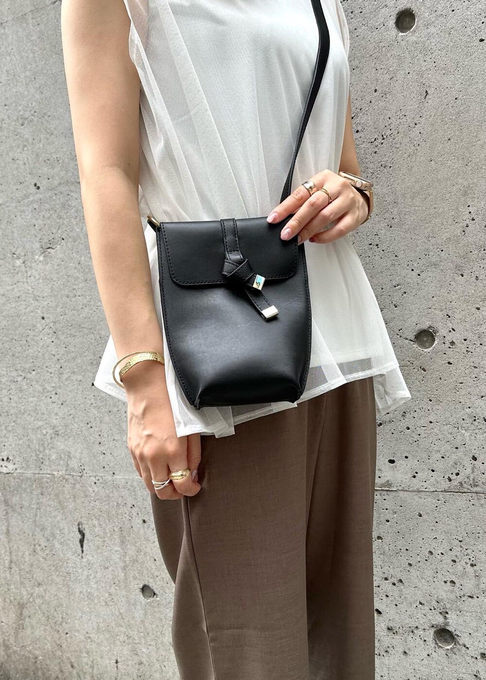 ブラック系のショルダーバッグ、ブラウン系のその他パンツ、ホワイト系のTシャツ/カットソーを着用したレディースの夏コーディネートの7枚目の写真